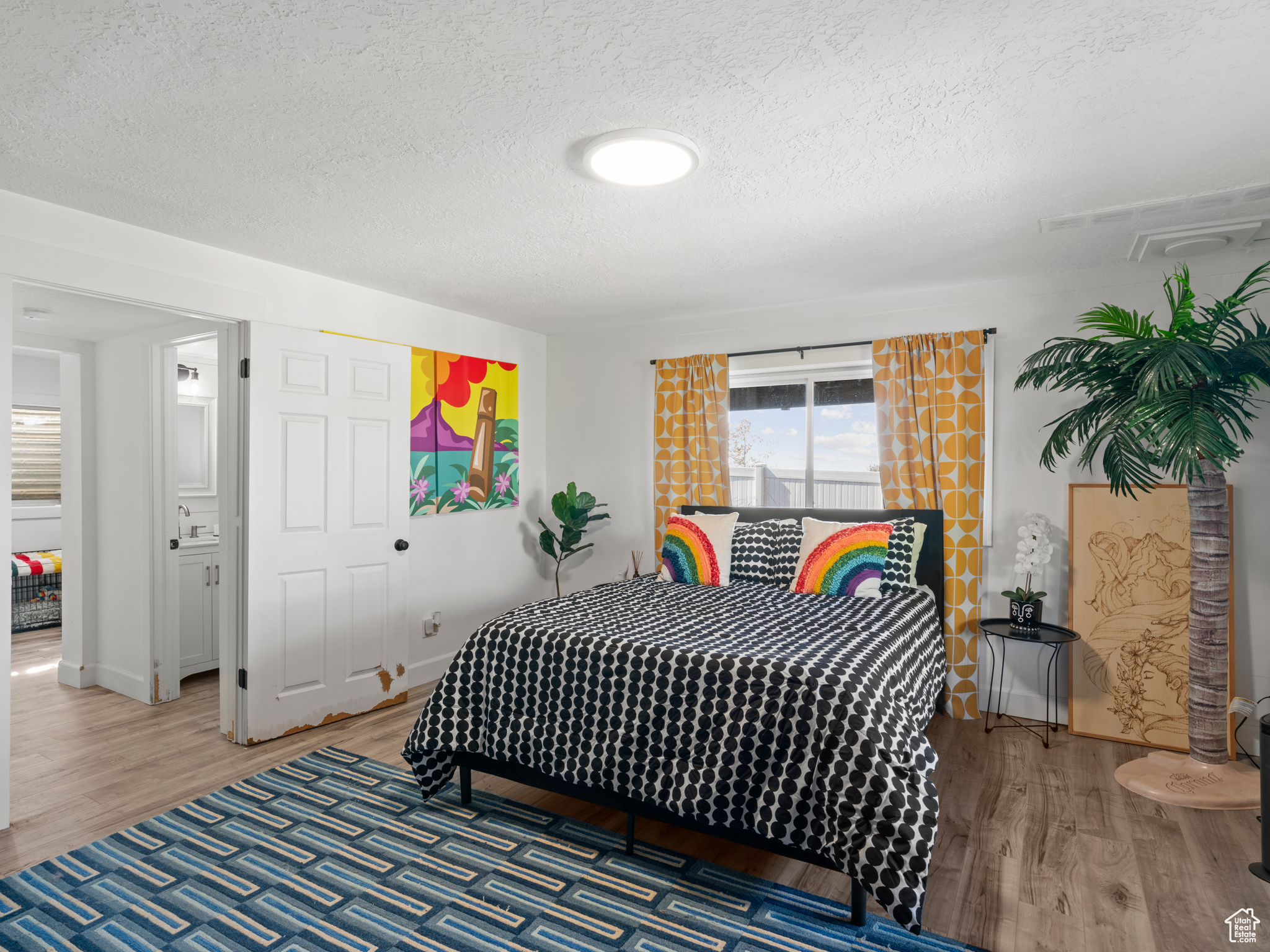 Family room set up as a guest bedroom with a textured ceiling and hardwood / wood-style floors