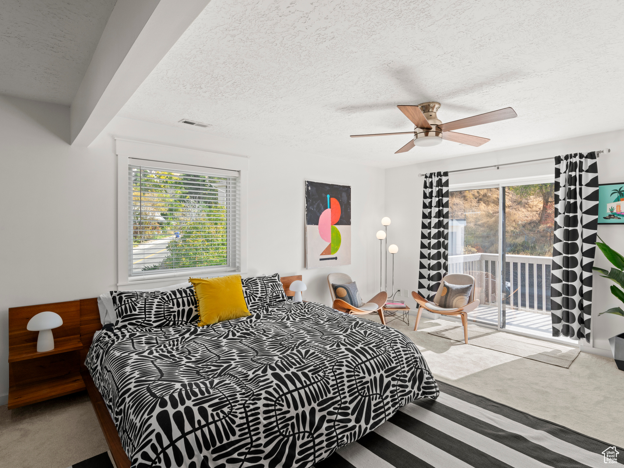 Primary bedroom featuring a textured ceiling, multiple windows, access to outside deck, and ceiling fan