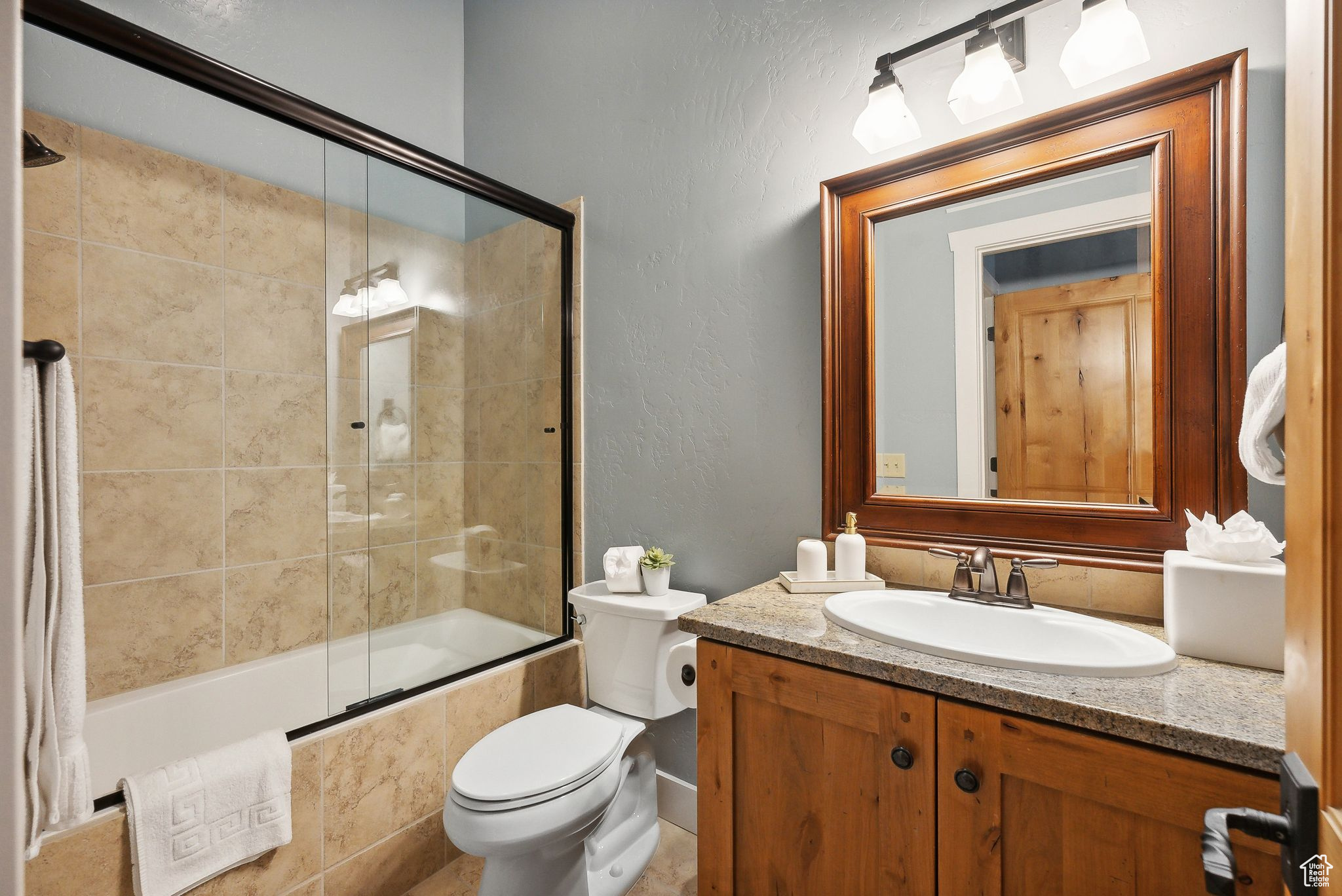 Full bathroom with toilet, enclosed tub / shower combo, and vanity