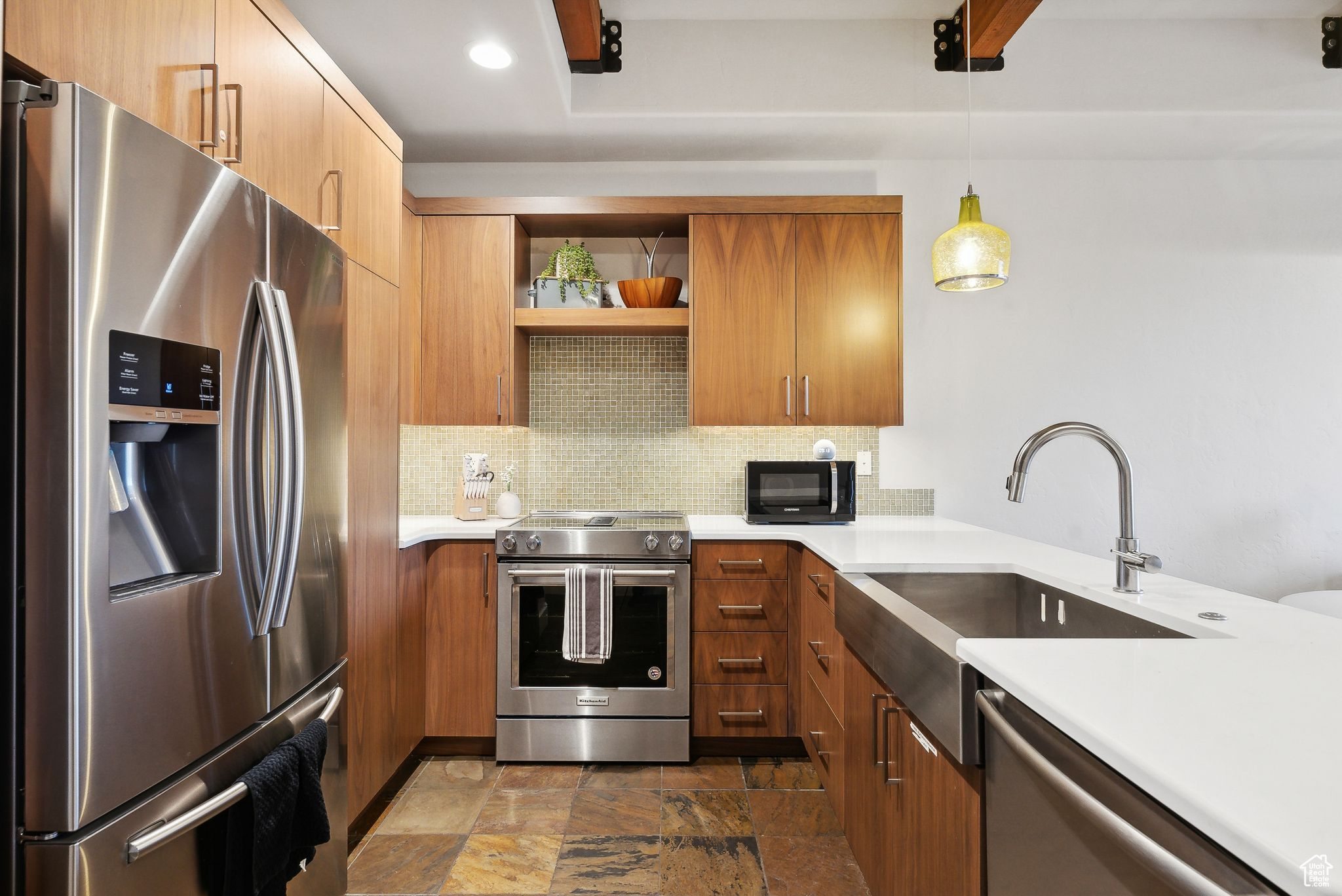 Kitchen with tasteful backsplash, appliances with stainless steel finishes, sink, and hanging light fixtures