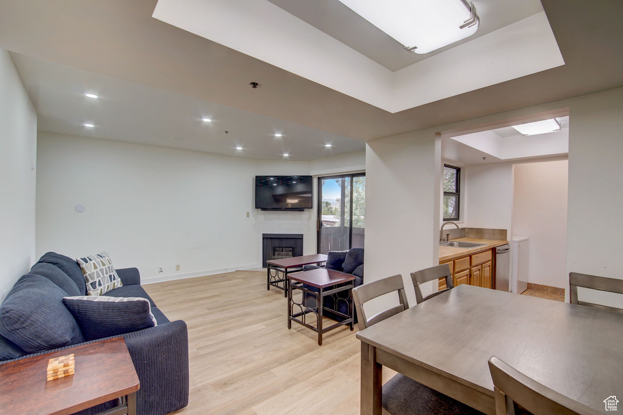 Living room with a raised ceiling, light hardwood / wood-style flooring, a fireplace, and sink