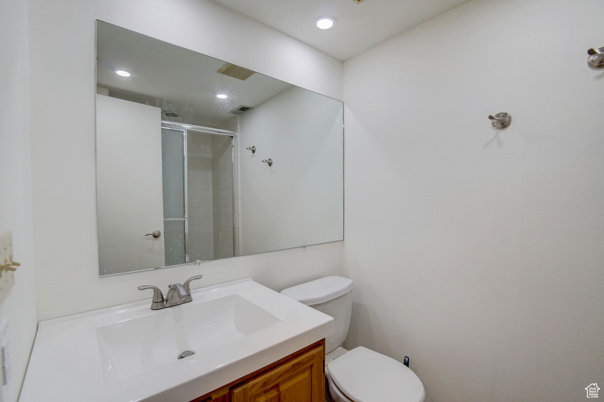 Bathroom with vanity, a shower with shower door, and toilet