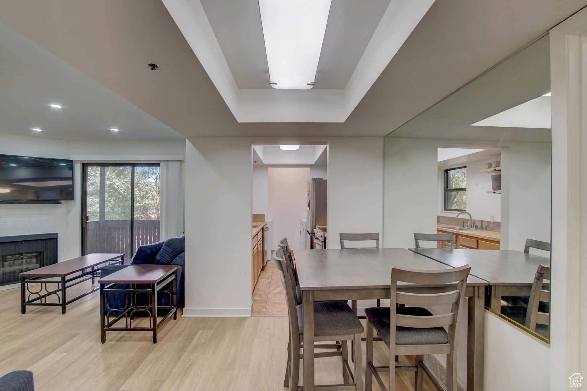 Dining area with a brick fireplace, light wood-type flooring, sink, and a healthy amount of sunlight