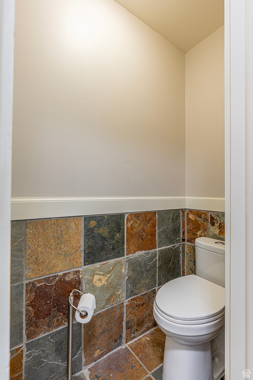 Bathroom featuring tile walls and toilet