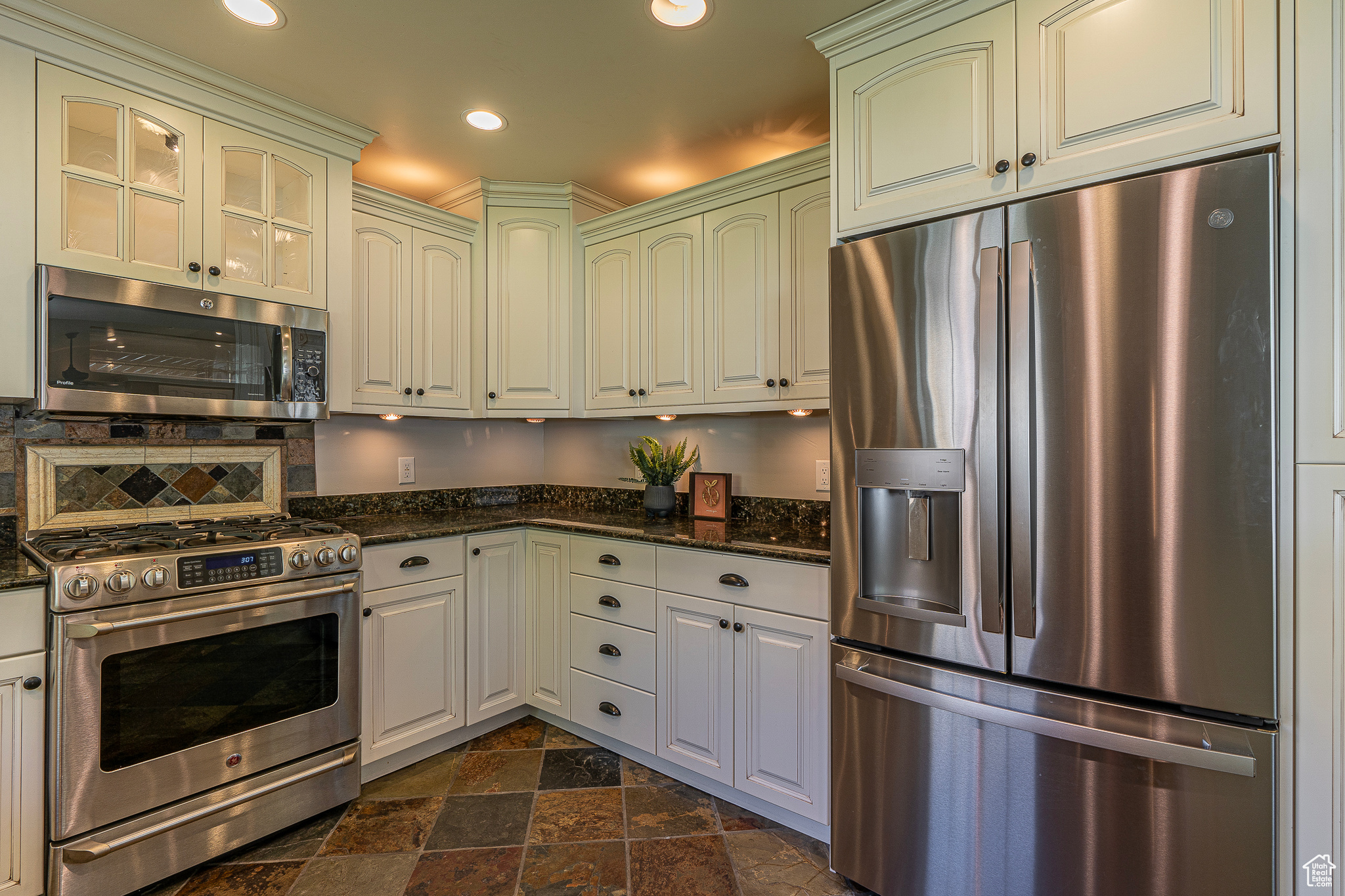 Kitchen featuring appliances with stainless steel finishes and dark stone counters