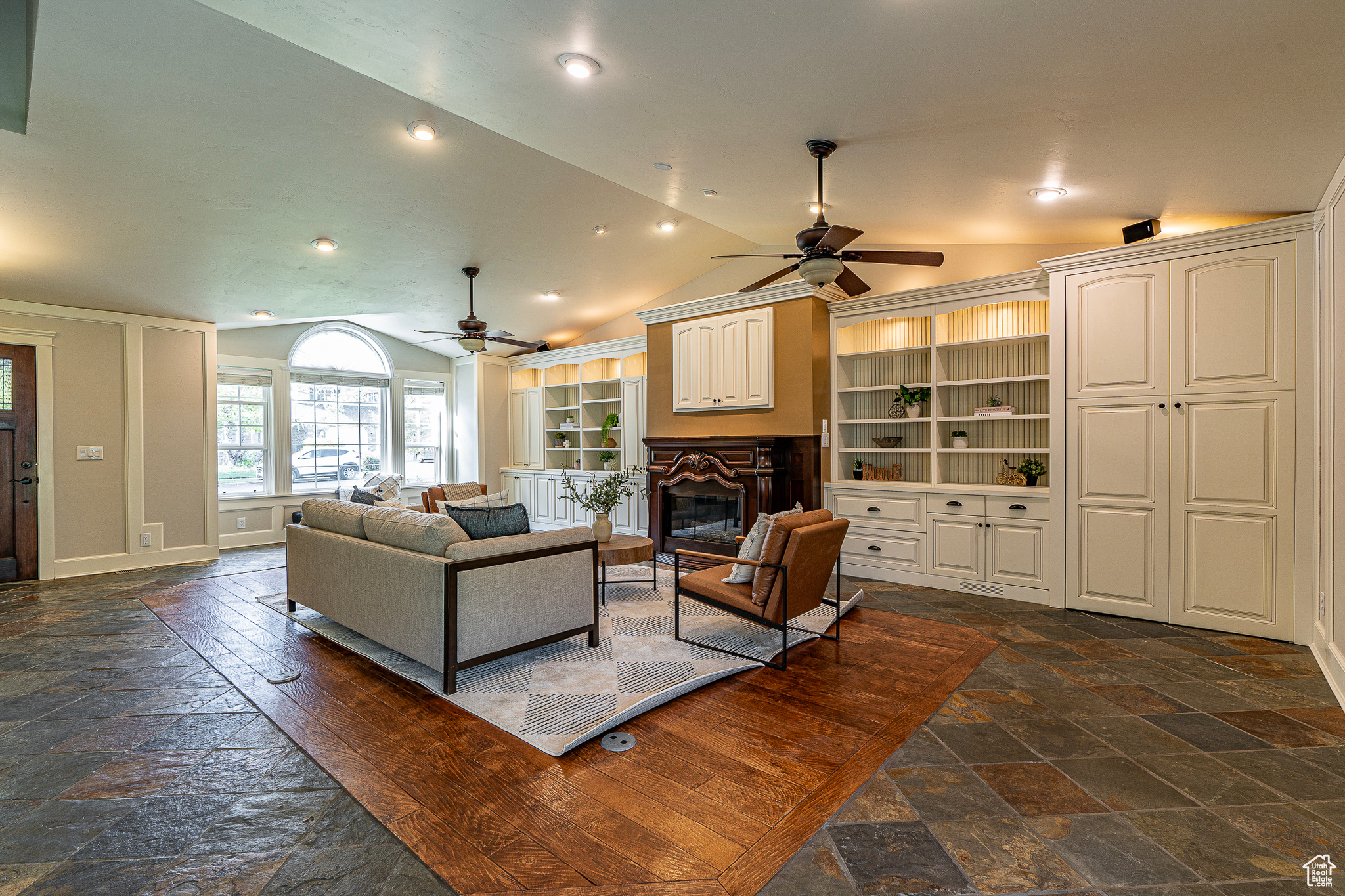 Living room featuring lofted ceiling, built in features, and ceiling fan