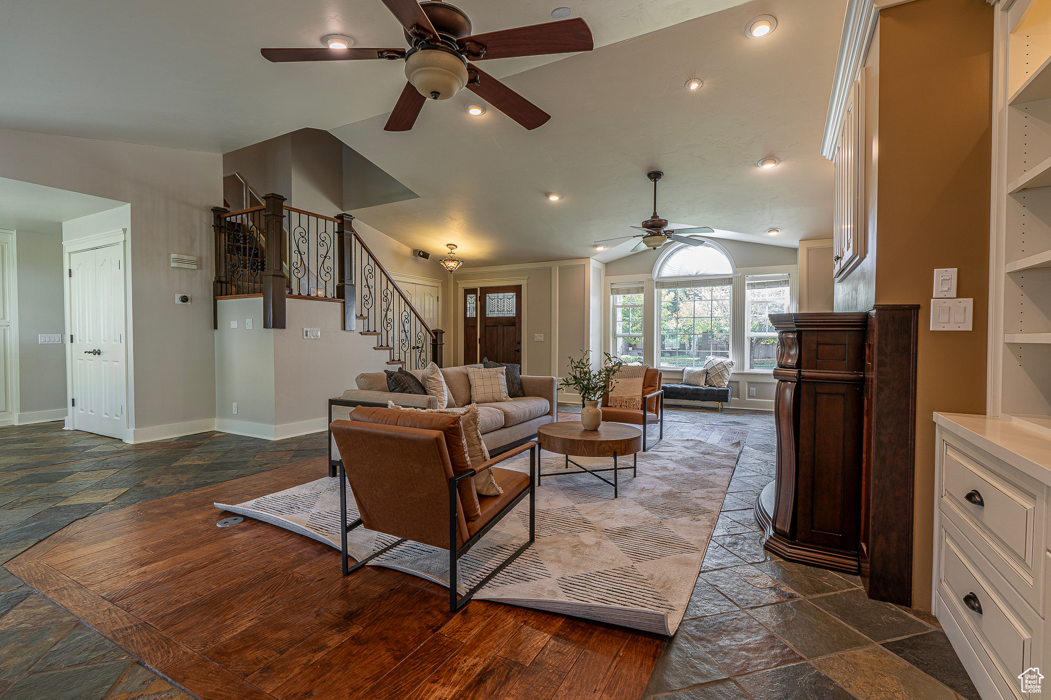 Living room with ceiling fan, lofted ceiling, and built in shelves