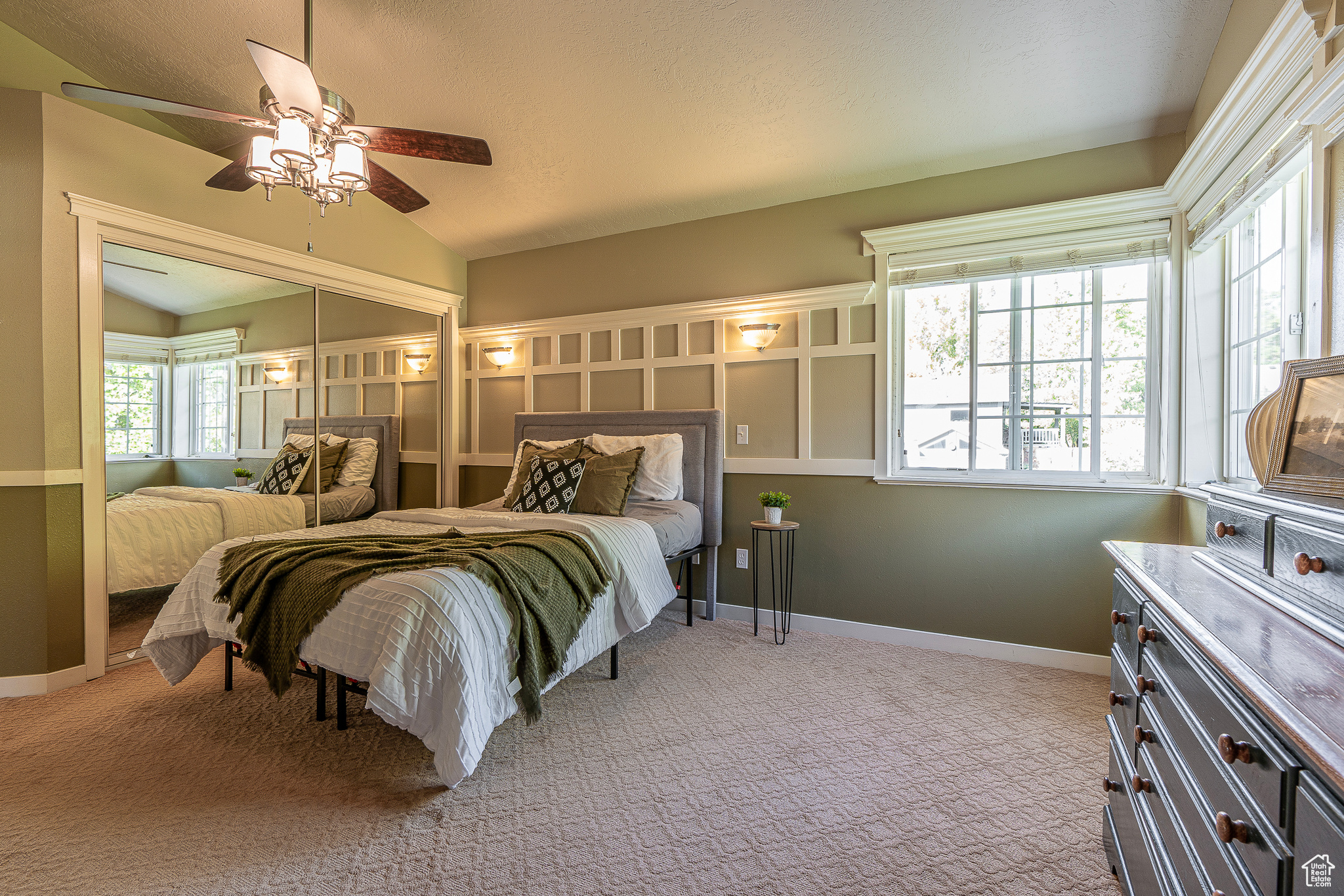 Carpeted bedroom featuring lofted ceiling, multiple windows, a closet, and ceiling fan