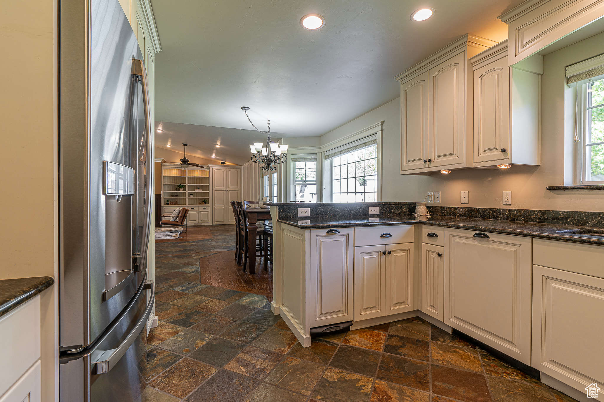 Kitchen featuring kitchen peninsula, a healthy amount of sunlight, decorative light fixtures, and stainless steel fridge with ice dispenser