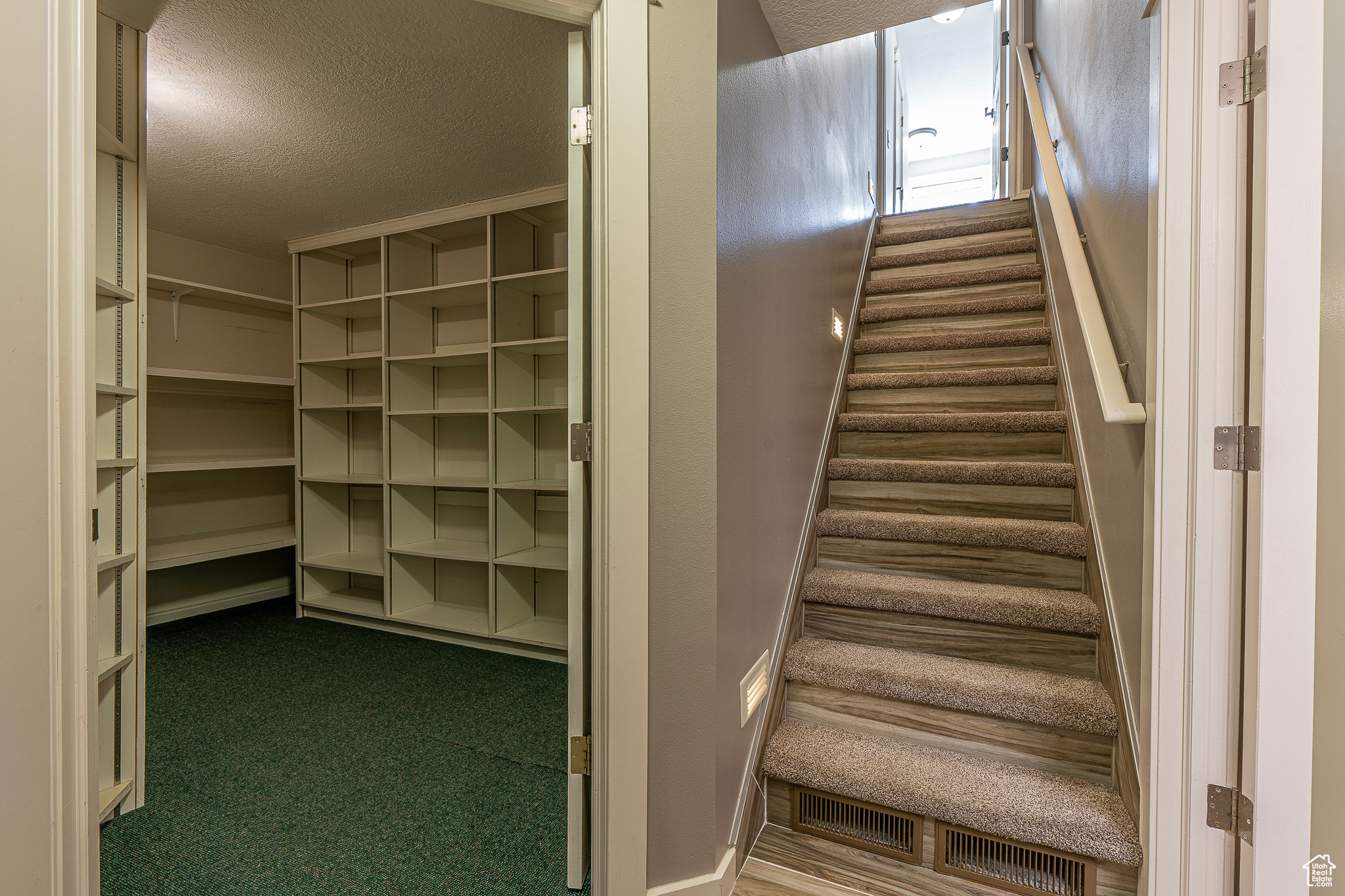 Stairway with carpet flooring and a textured ceiling