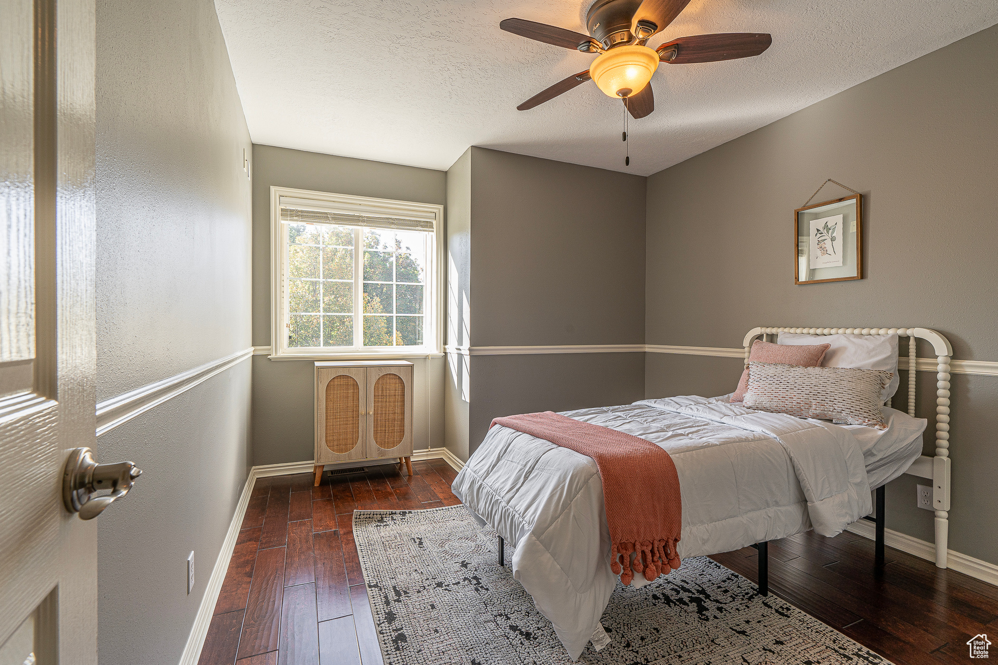 Bedroom with a textured ceiling, dark wood-type flooring, and ceiling fan