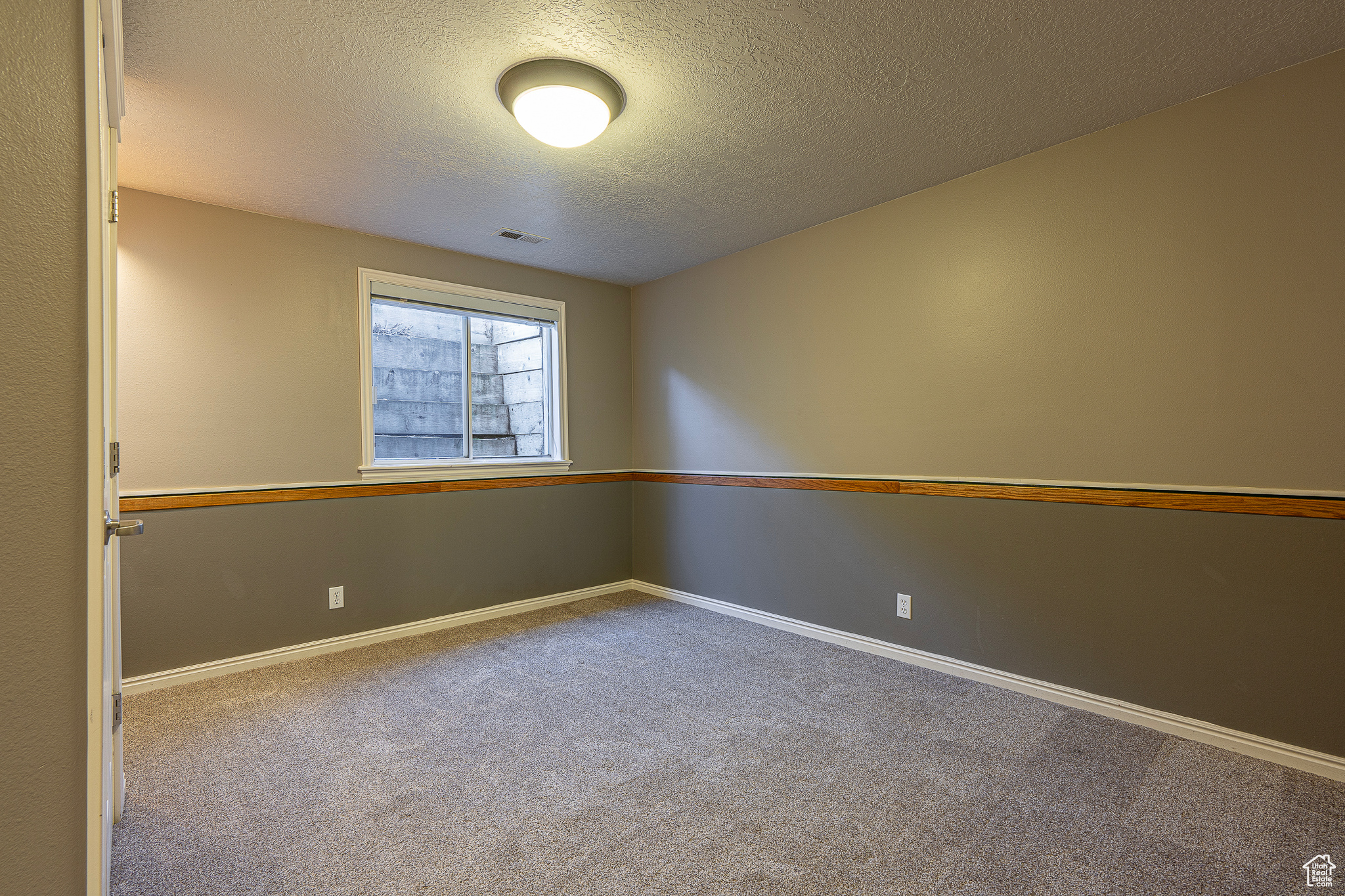 Unfurnished room featuring carpet and a textured ceiling