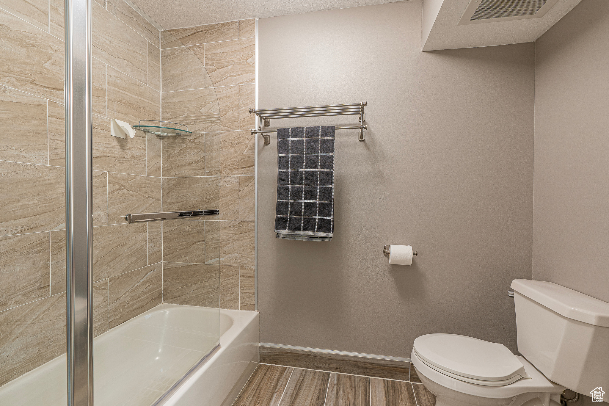 Bathroom featuring toilet, a textured ceiling, and tiled shower / bath