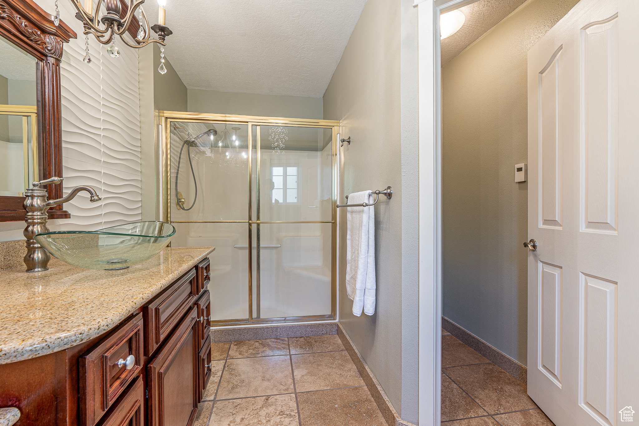 Bathroom featuring vanity, a textured ceiling, and a shower with shower door