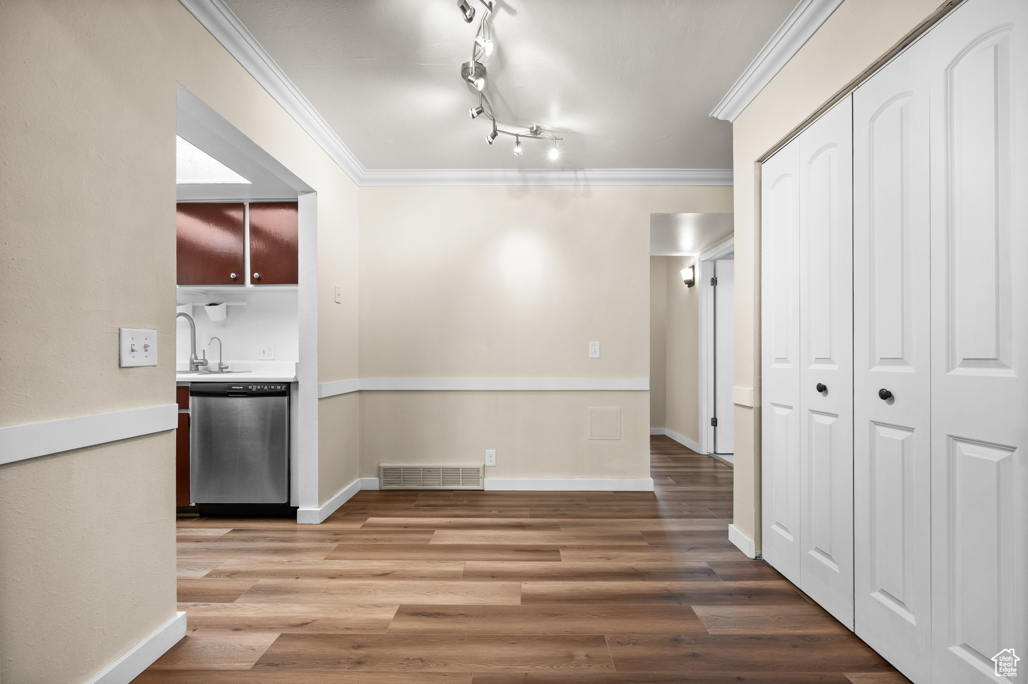 Unfurnished dining area with crown molding, hardwood / wood-style floors, and track lighting