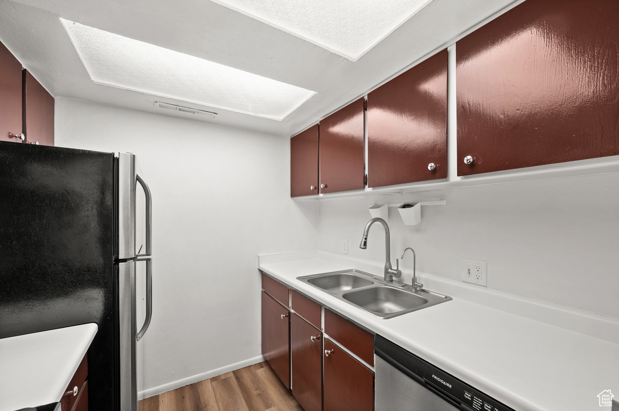 Kitchen with light hardwood / wood-style floors, stainless steel appliances, and sink