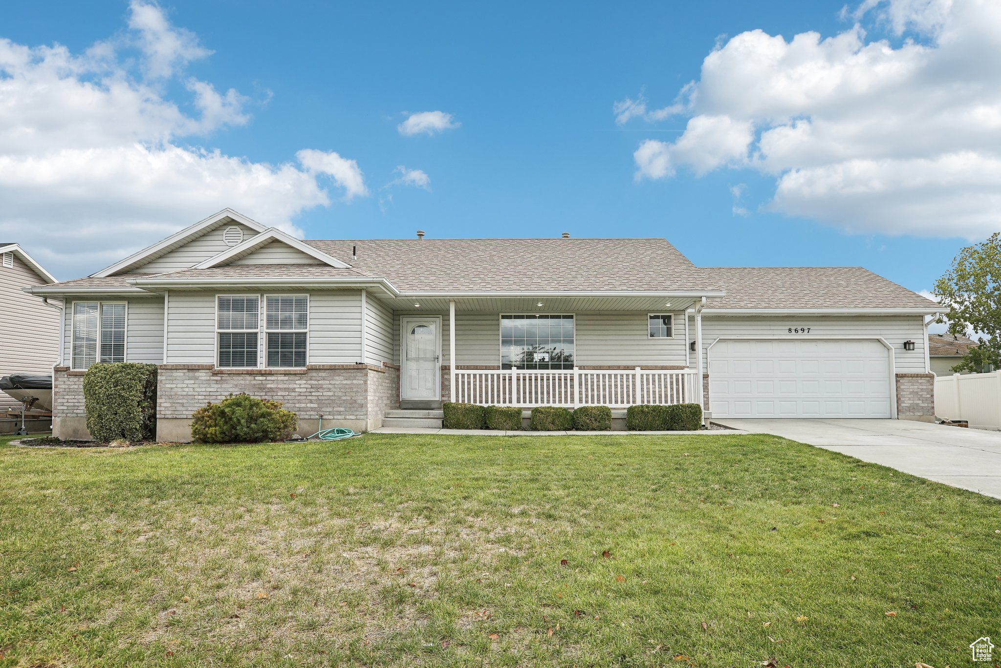 Single story home featuring a front yard, a garage, and a porch