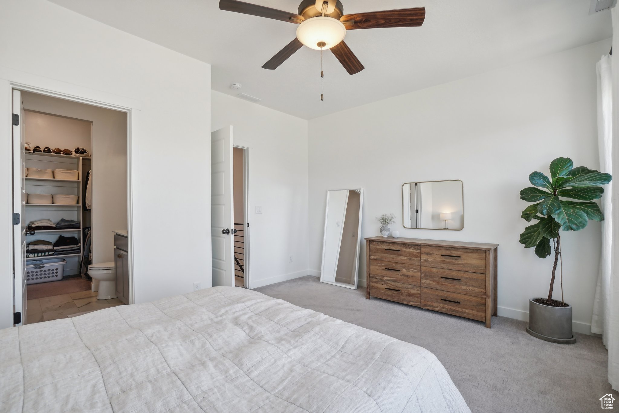 Bedroom featuring a closet, light carpet, ensuite bath, a spacious closet, and ceiling fan