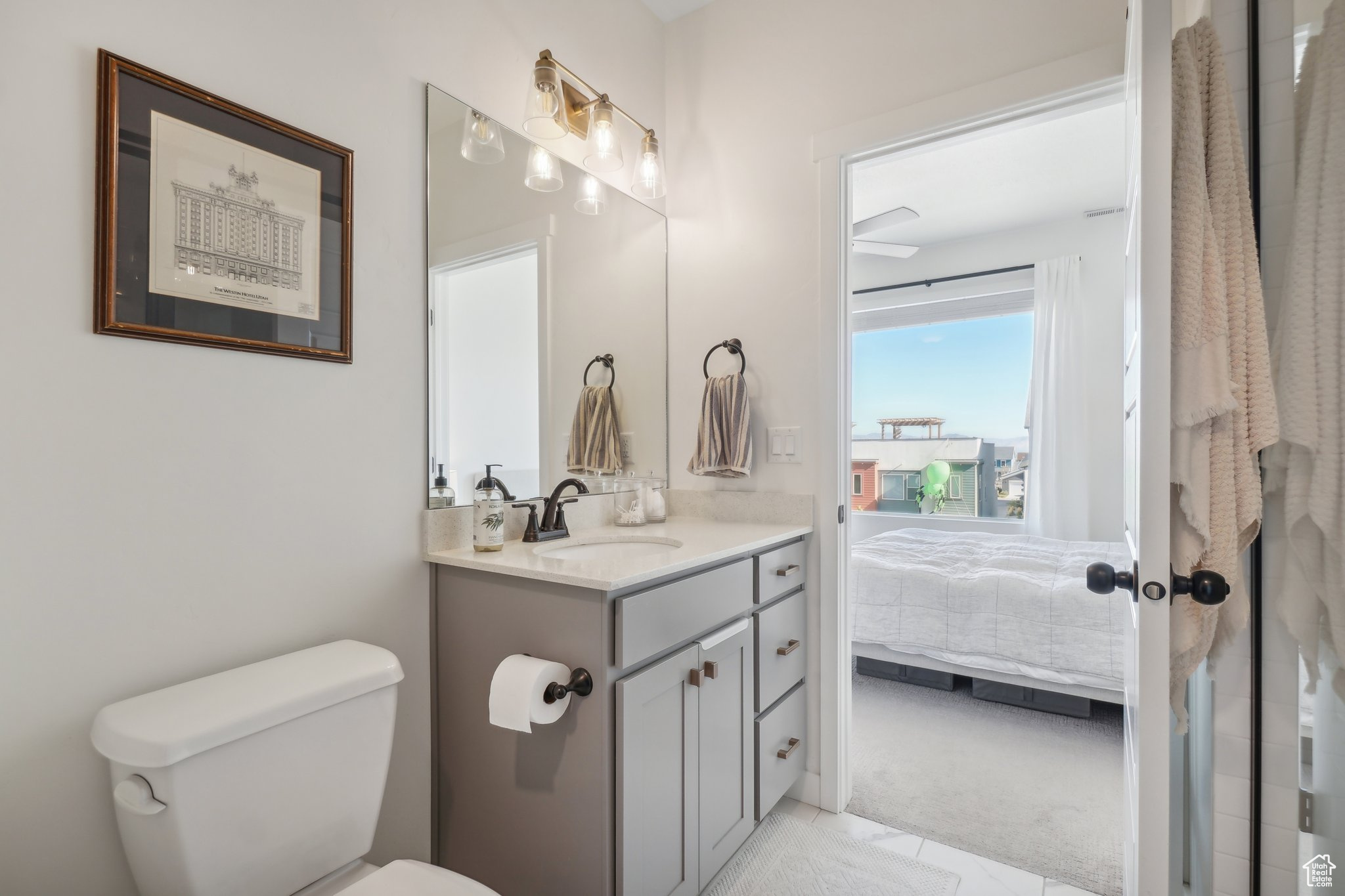 Bathroom featuring vanity, toilet, and ceiling fan