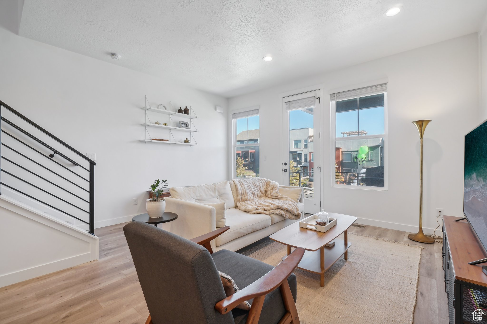 Living room with a textured ceiling and light hardwood / wood-style flooring