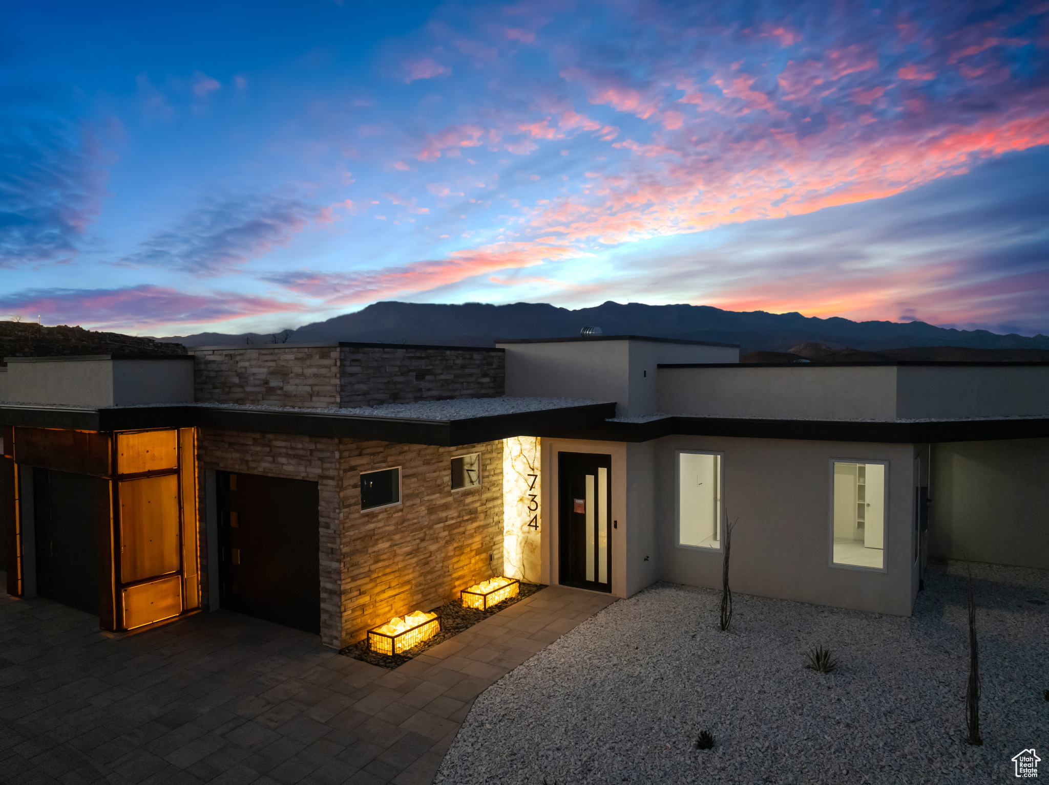 Back house at dusk featuring a mountain view and a patio area