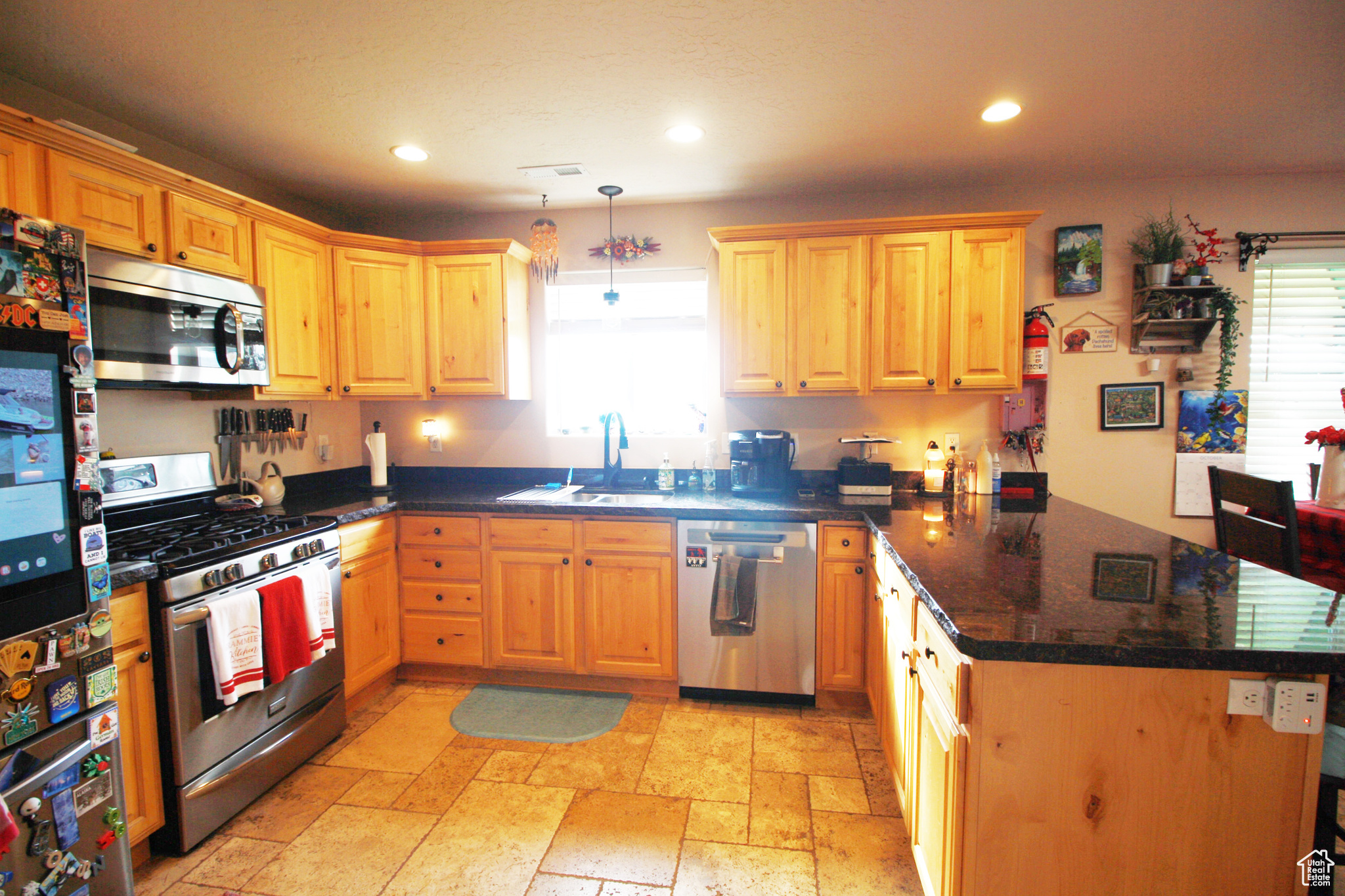 Kitchen featuring sink, appliances with stainless steel finishes, gas stove, kitchen peninsula, and pendant lighting