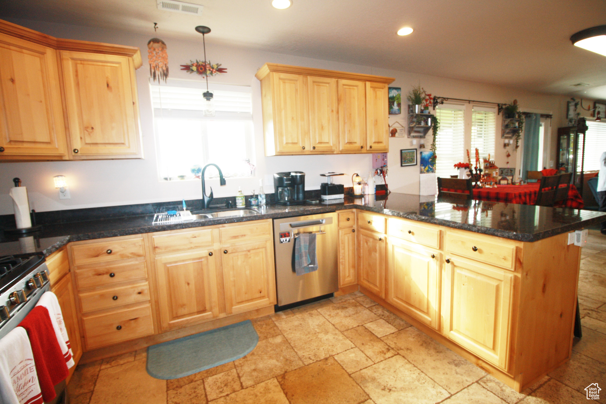 Kitchen with sink, kitchen peninsula, hanging light fixtures, stainless steel appliances, and dark stone countertops