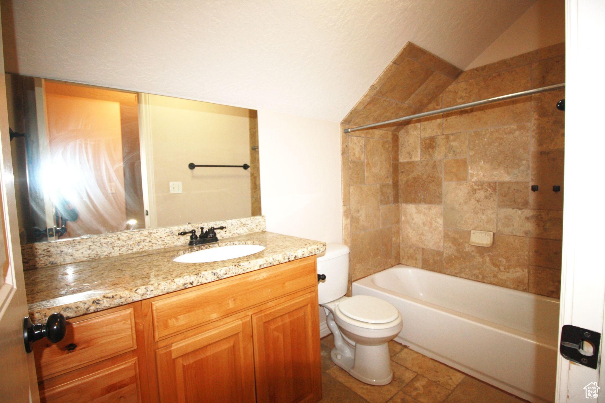 Full bathroom 3, with vanity, toilet, lofted ceiling, and tiled shower / bath