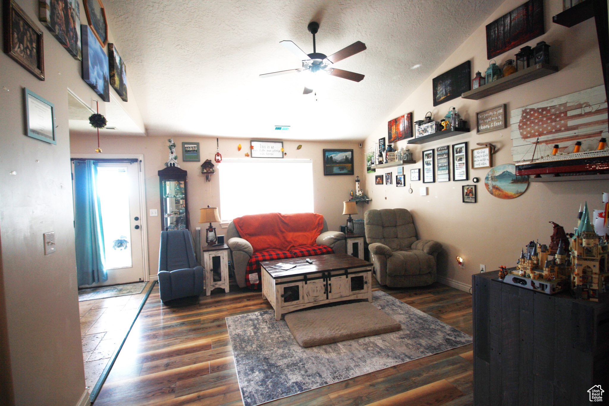 Living room with lofted ceiling, dark hardwood / wood-style floors, a textured ceiling, and a wealth of natural light