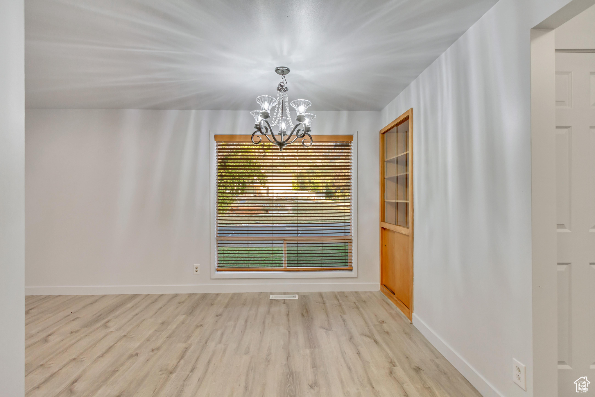 Unfurnished room featuring an inviting chandelier and light wood-type flooring