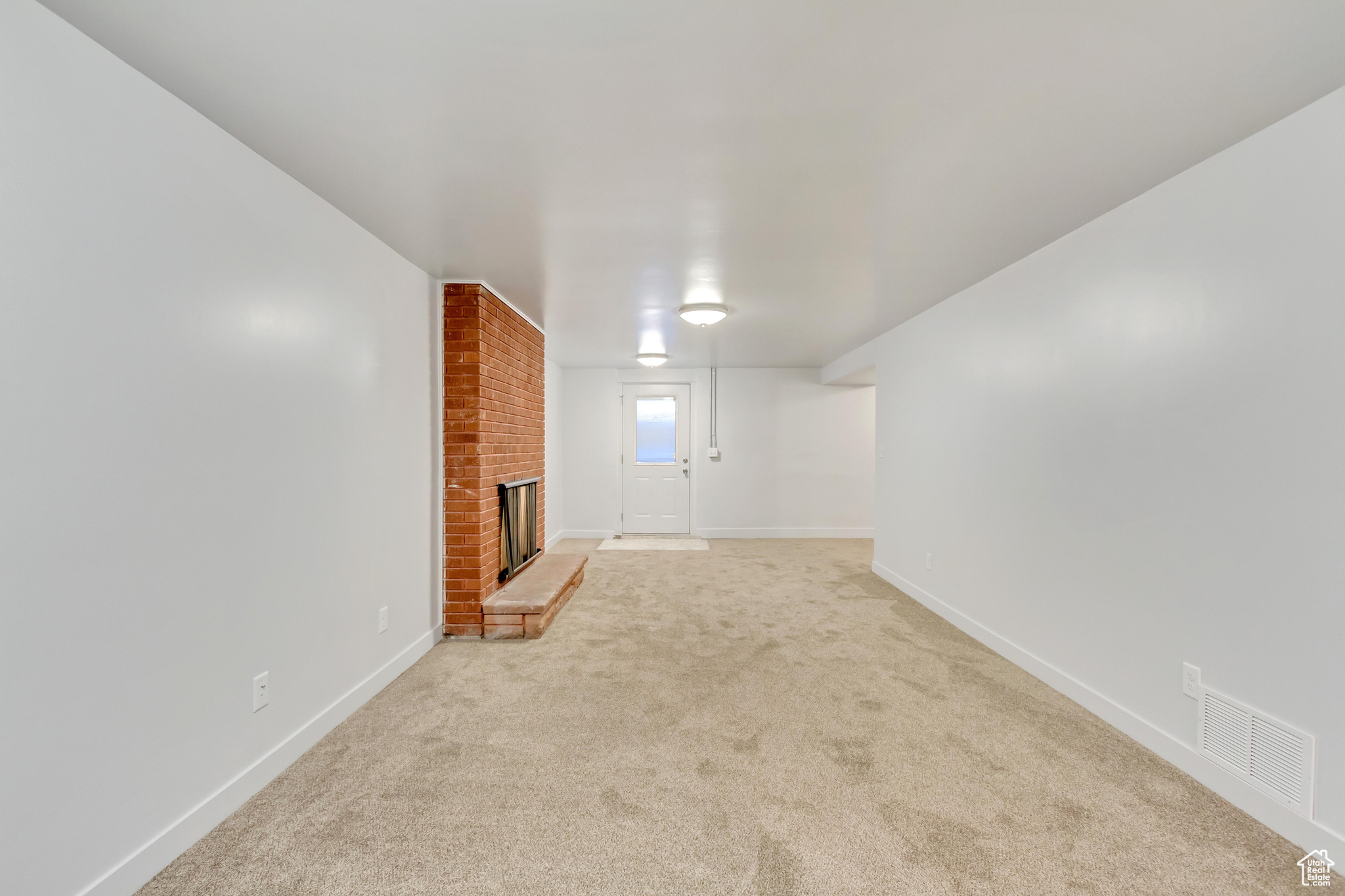 Unfurnished living room with light carpet and a fireplace