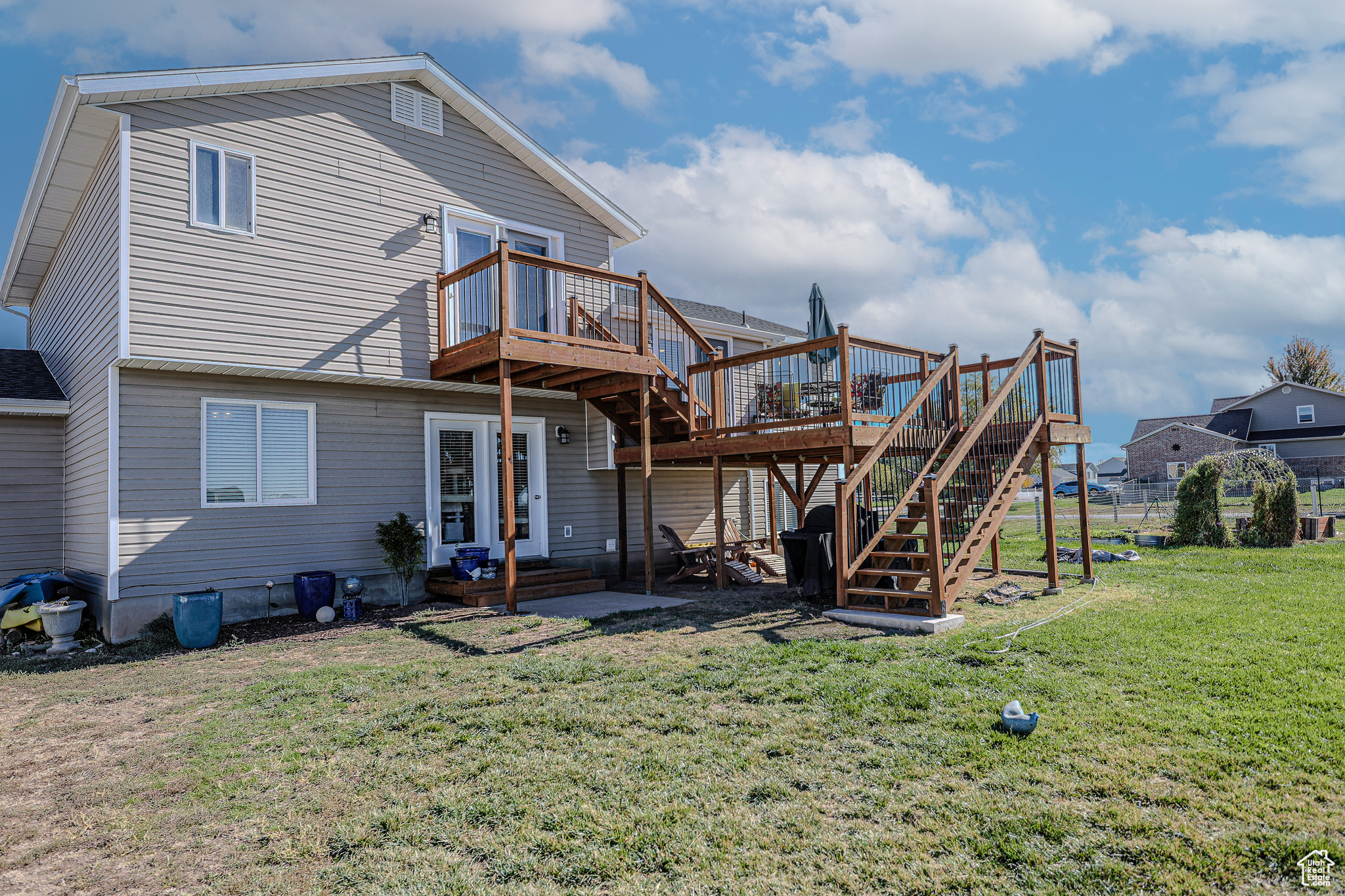 Back of property featuring a yard, a wooden deck, and a patio