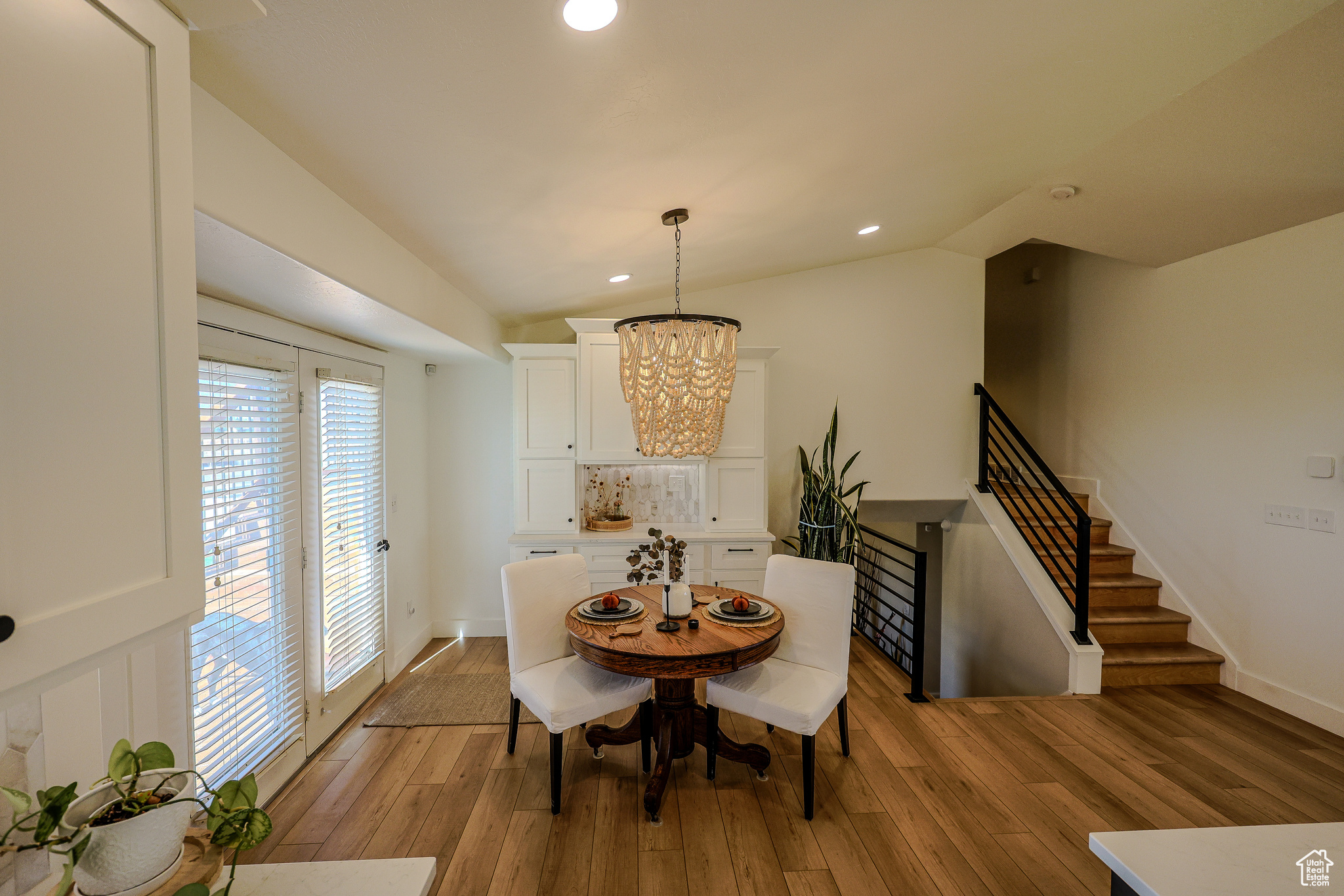 Dining room with lofted ceiling, light wood-type flooring, and an inviting chandelier