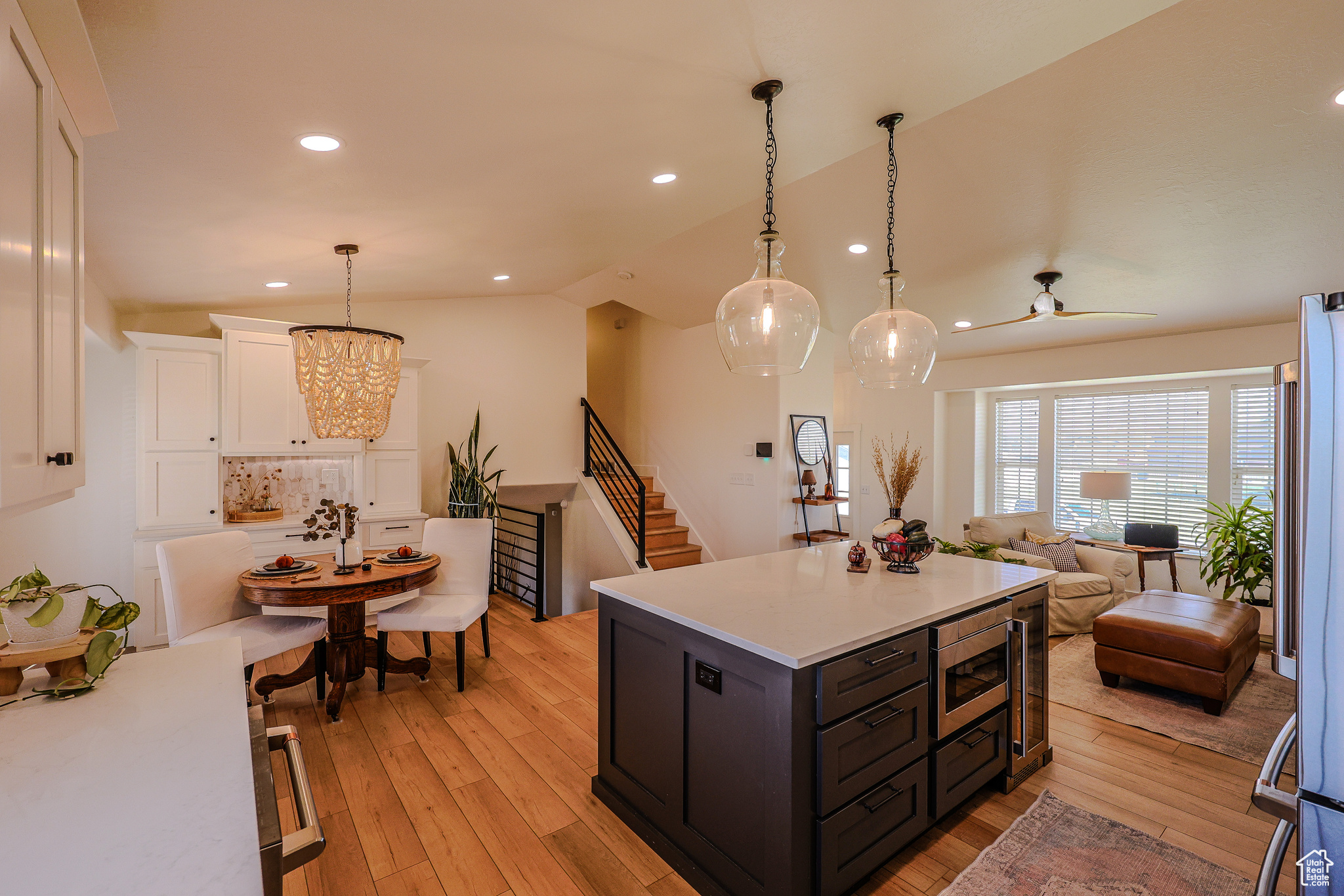 Kitchen with backsplash, hanging light fixtures, light hardwood / wood-style floors, lofted ceiling, and white cabinets