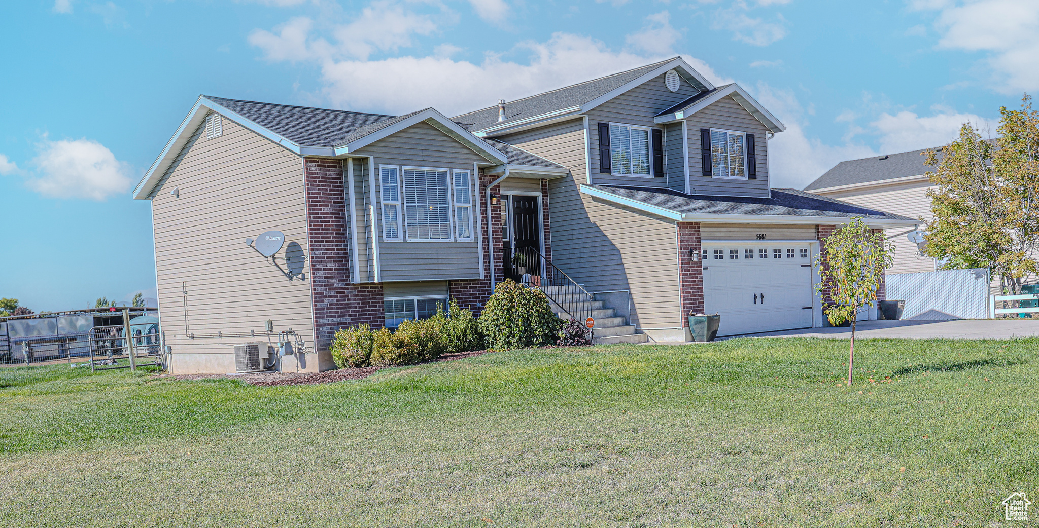 View of front of house with central AC, a front yard, and a garage