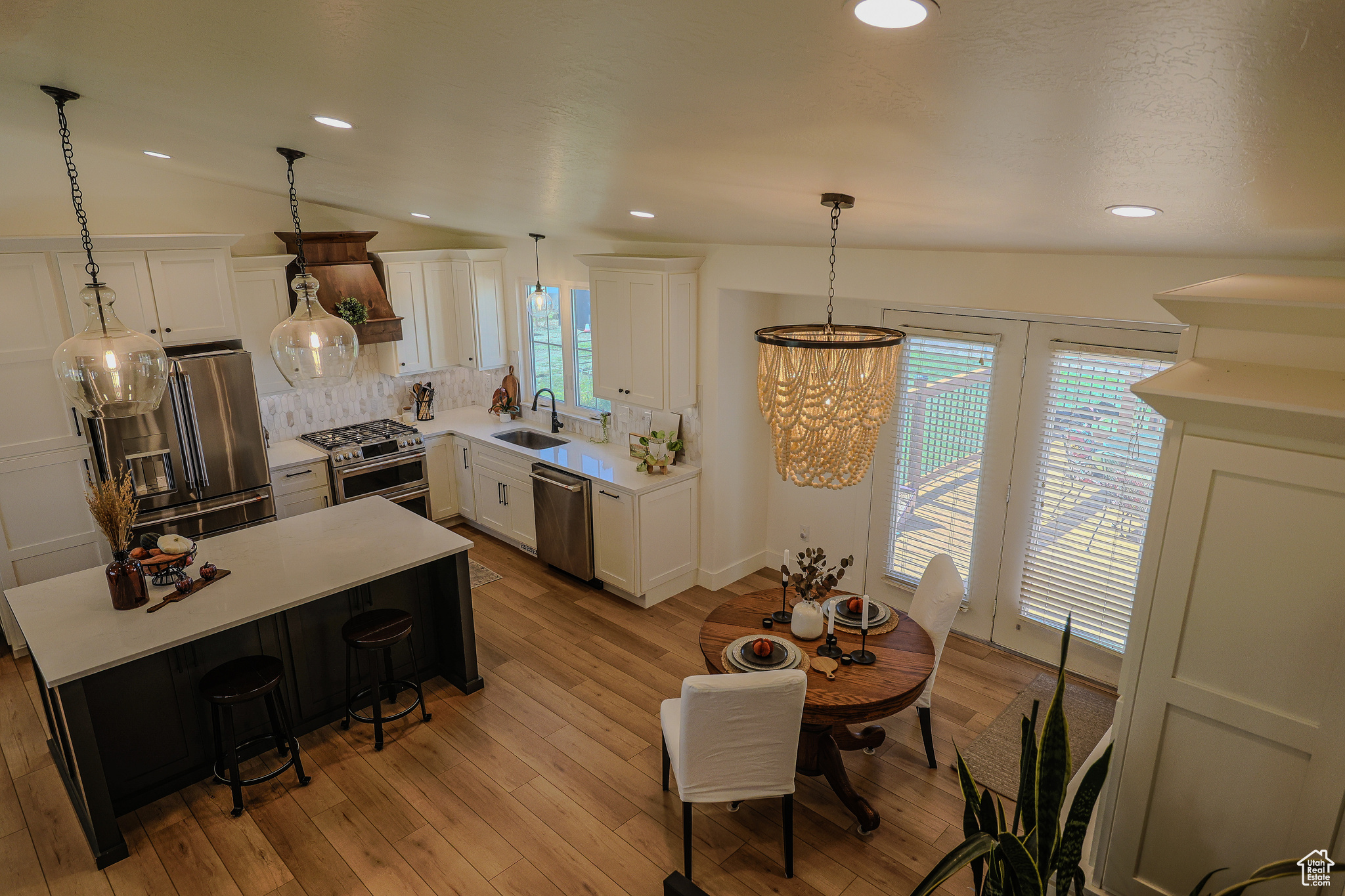 Kitchen featuring white cabinetry, appliances with stainless steel finishes, lofted ceiling, and a kitchen island