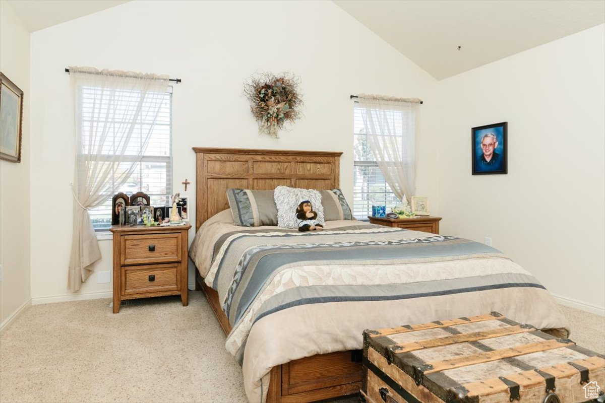 Carpeted bedroom with lofted ceiling and multiple windows