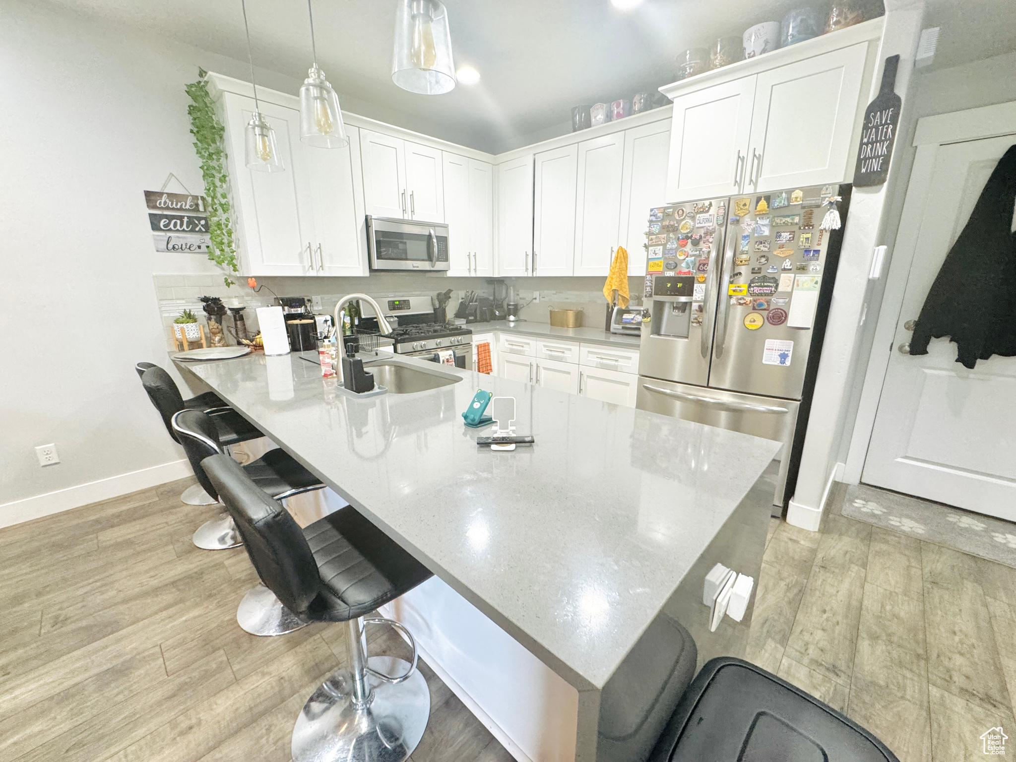 Kitchen with sink, appliances with stainless steel finishes, hanging light fixtures, and a breakfast bar