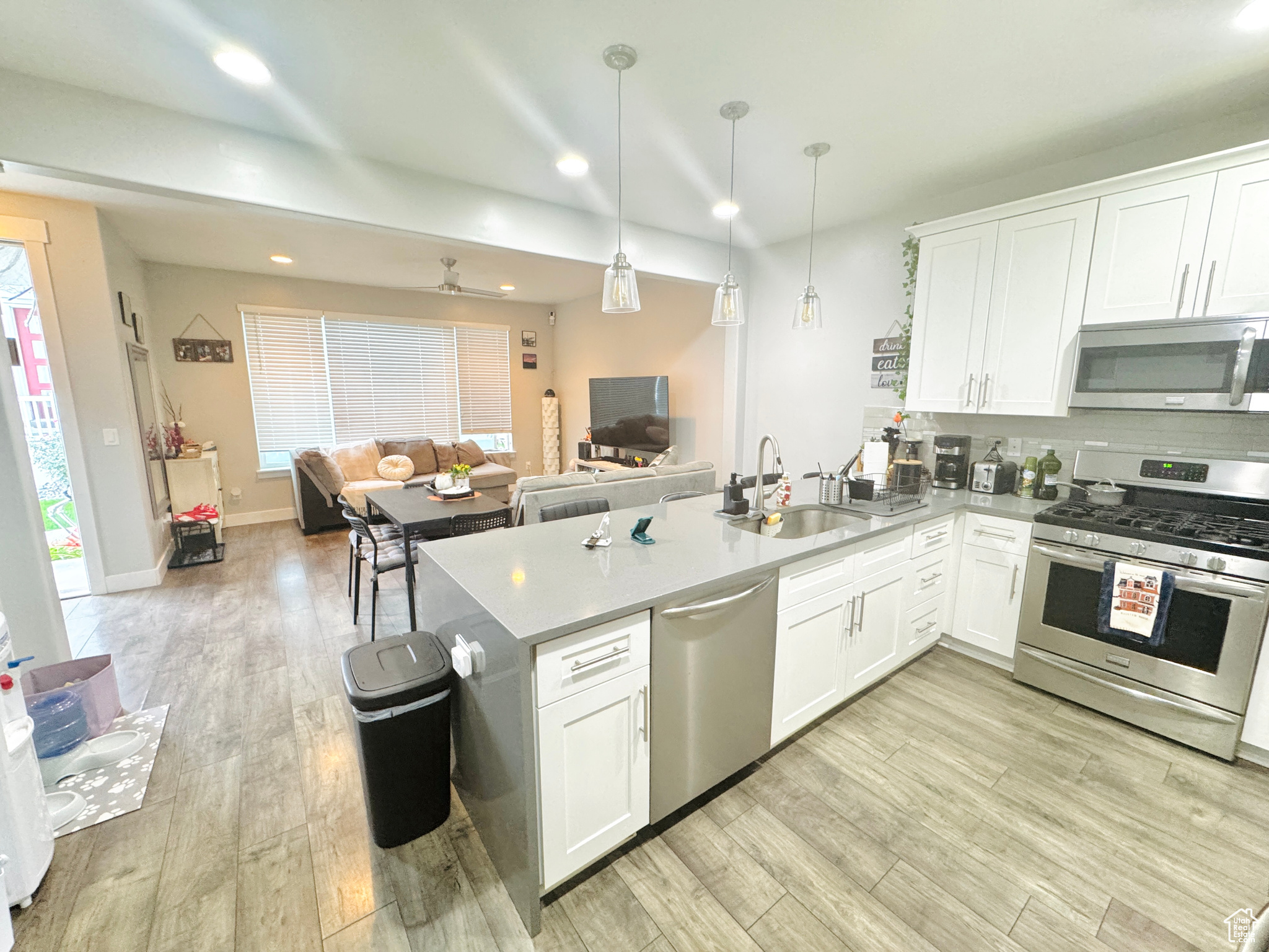 Kitchen featuring hanging light fixtures, a wealth of natural light, sink, white cabinets, and appliances with stainless steel finishes