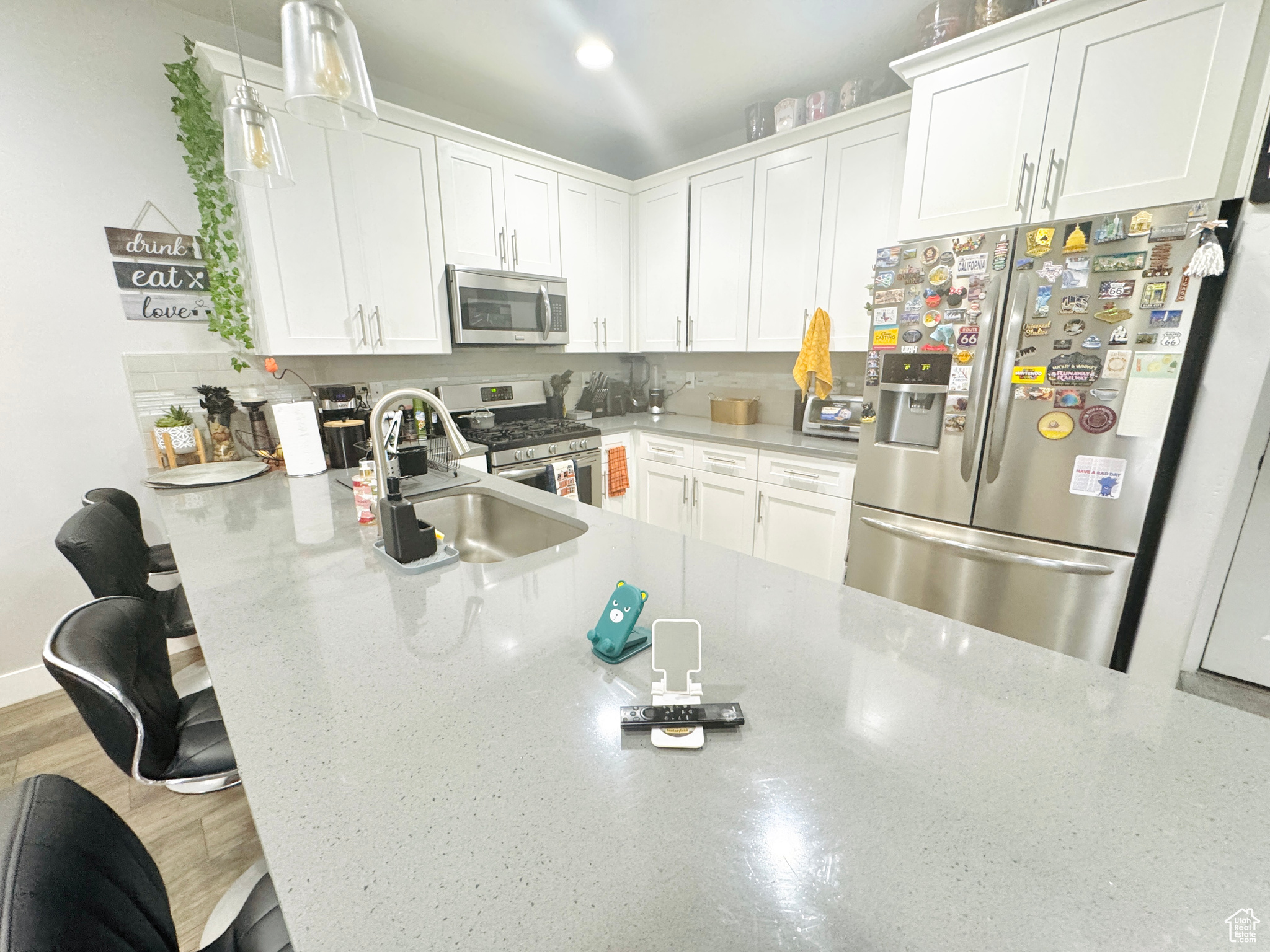 Kitchen with white cabinetry, appliances with stainless steel finishes, sink, and a kitchen bar