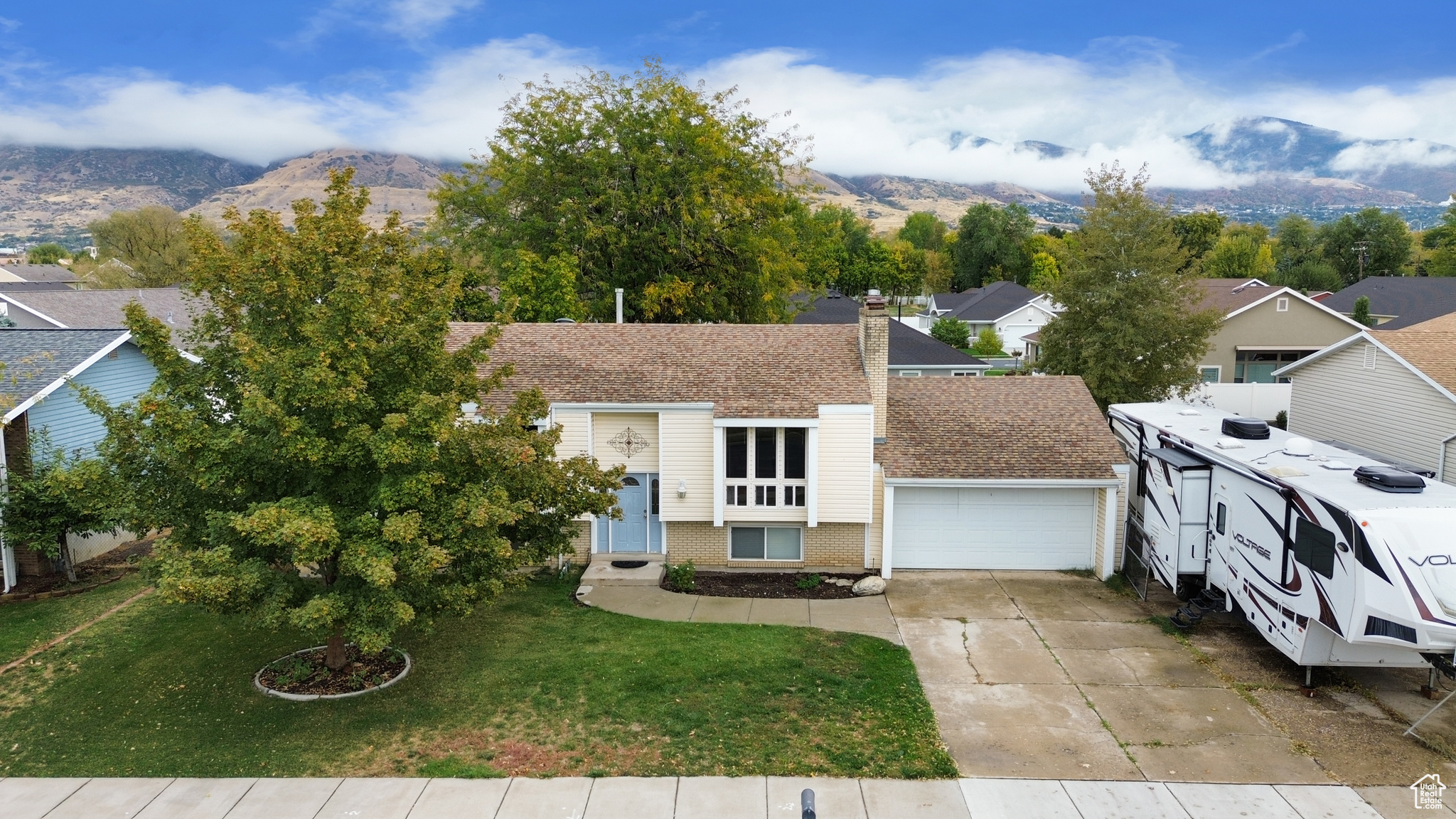 View of front of house featuring a mountain view, a front lawn, and a garage