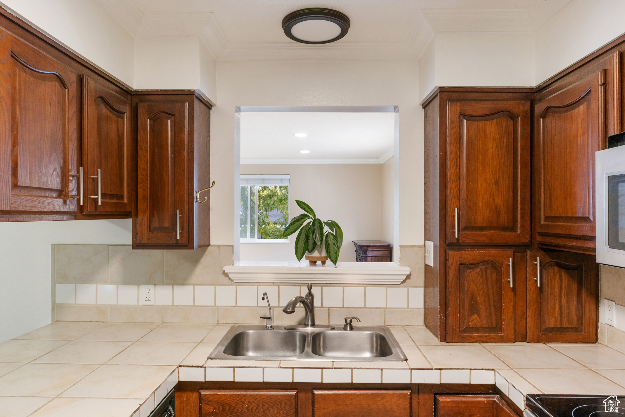 Kitchen with crown molding, decorative backsplash, sink, and tile countertops