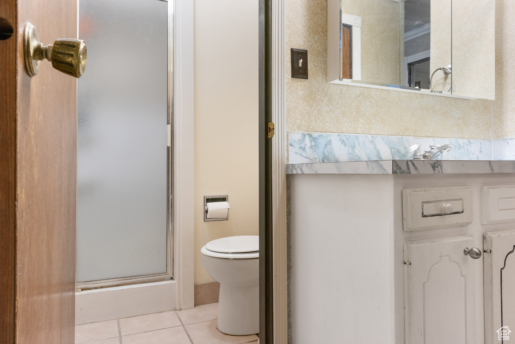 Primary Bathroom featuring a shower with door, toilet, and tile patterned flooring