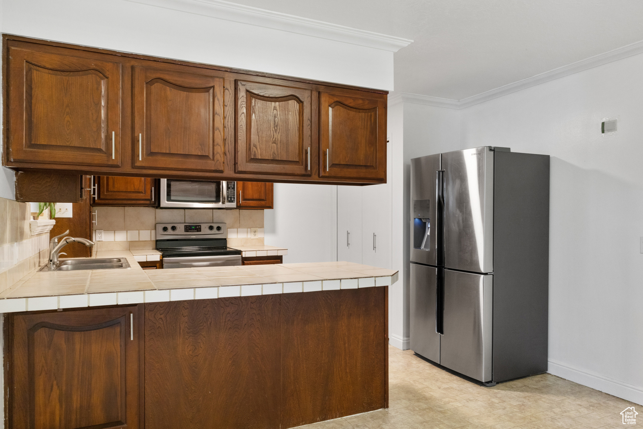 Kitchen featuring sink, appliances with stainless steel finishes, kitchen peninsula, and tile counters