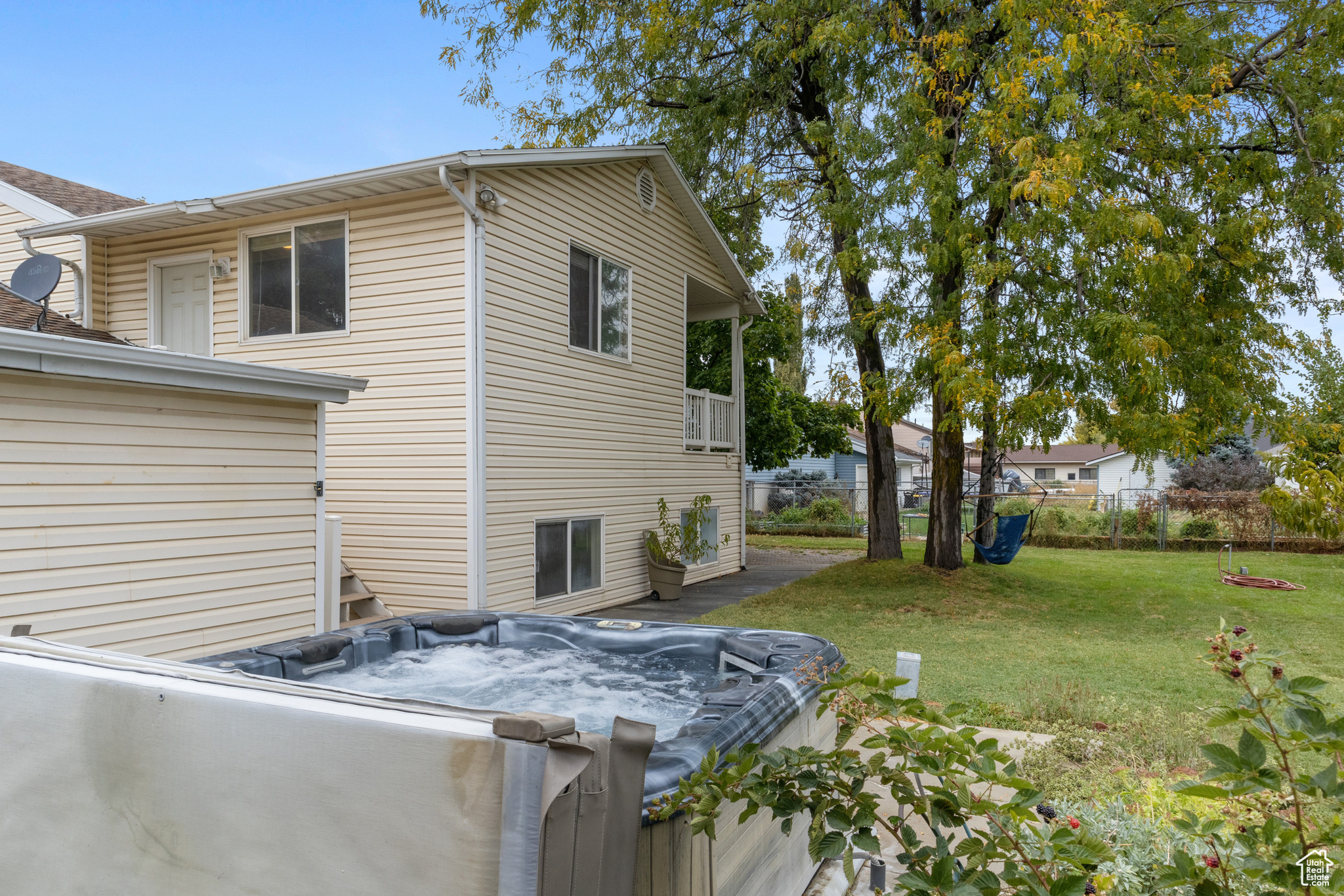 View of back of home featuring a hot tub and a lawn