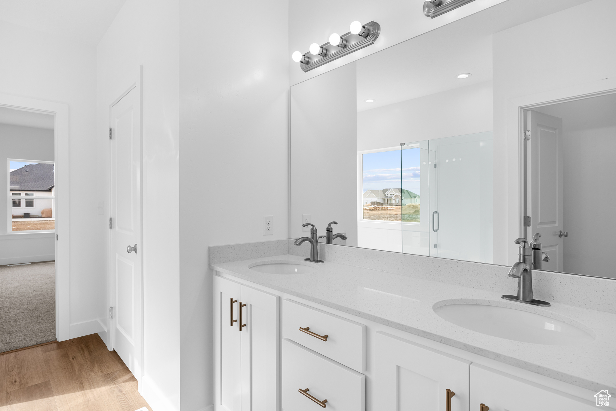 Bathroom featuring double vanity, wood finished floors, a sink, and baseboards