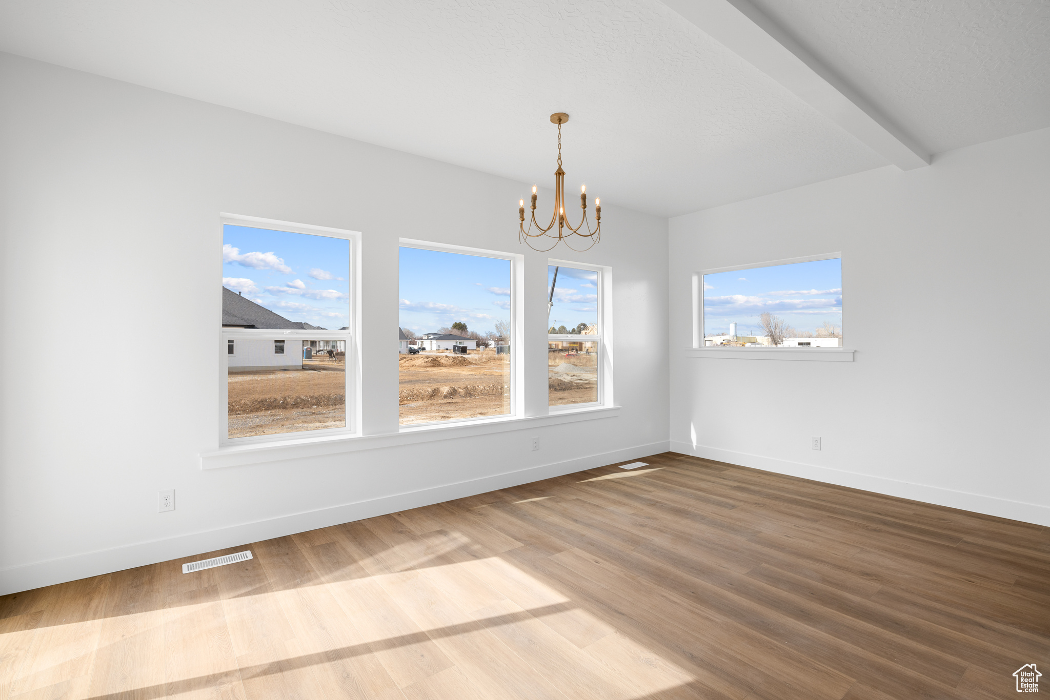 Unfurnished dining area featuring baseboards, visible vents, a chandelier, and wood finished floors