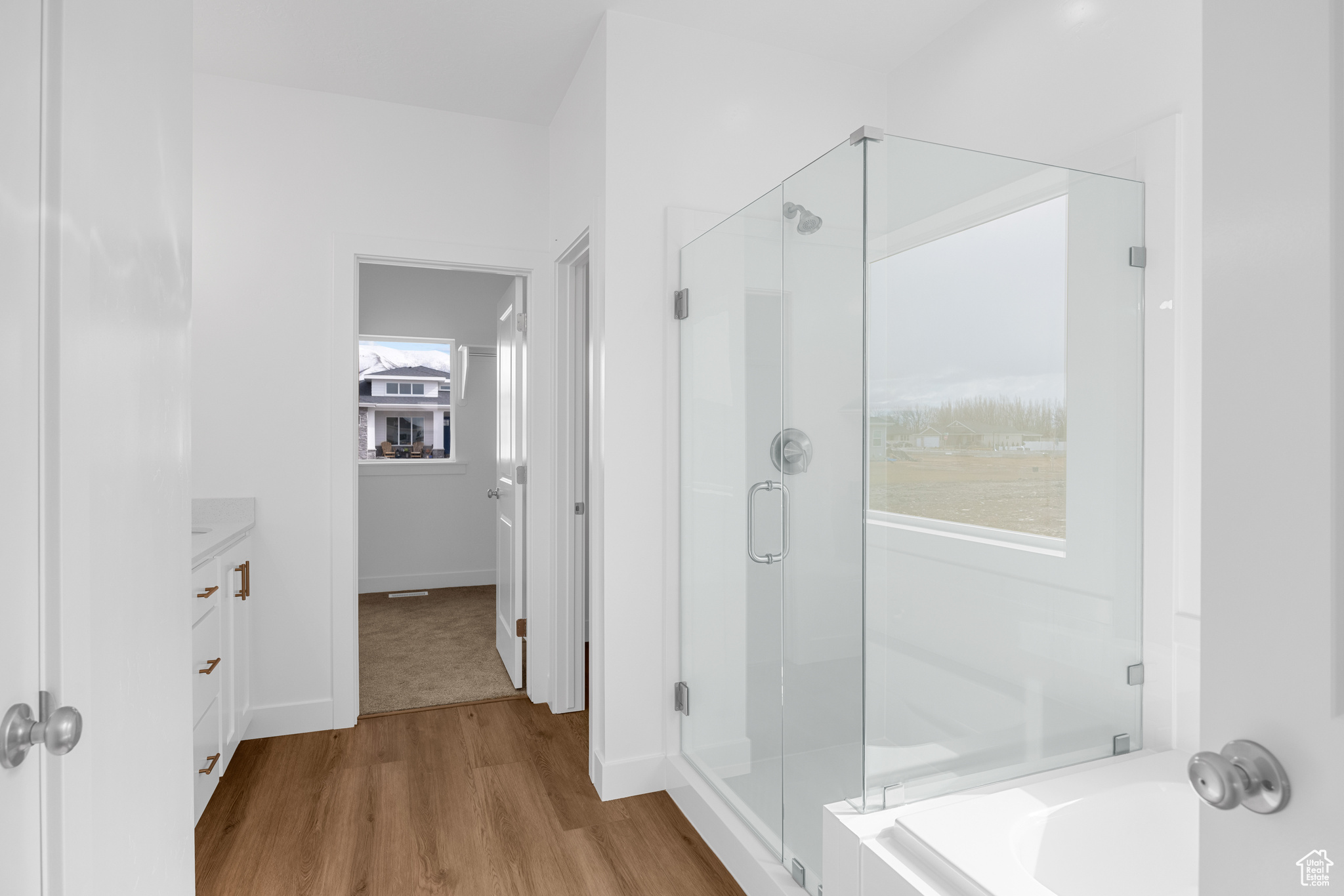 Full bath with a garden tub, a shower stall, baseboards, and wood finished floors