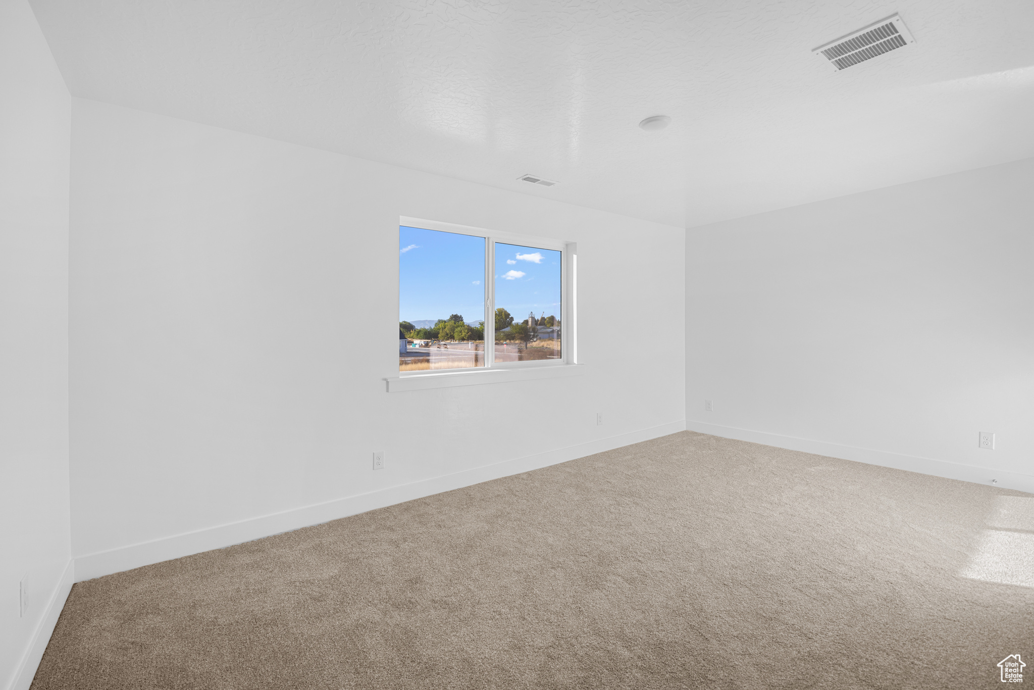 Empty room featuring baseboards, visible vents, and carpet flooring