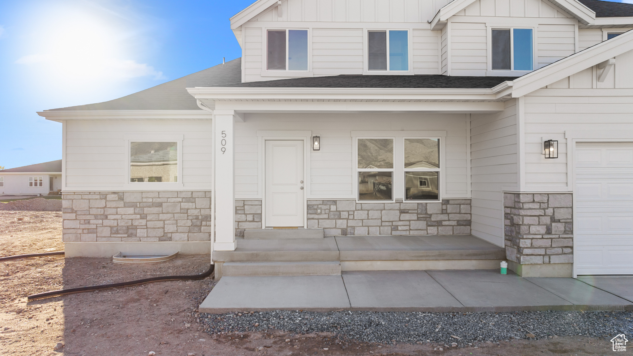 Doorway to property with stone siding, a porch, board and batten siding, and roof with shingles